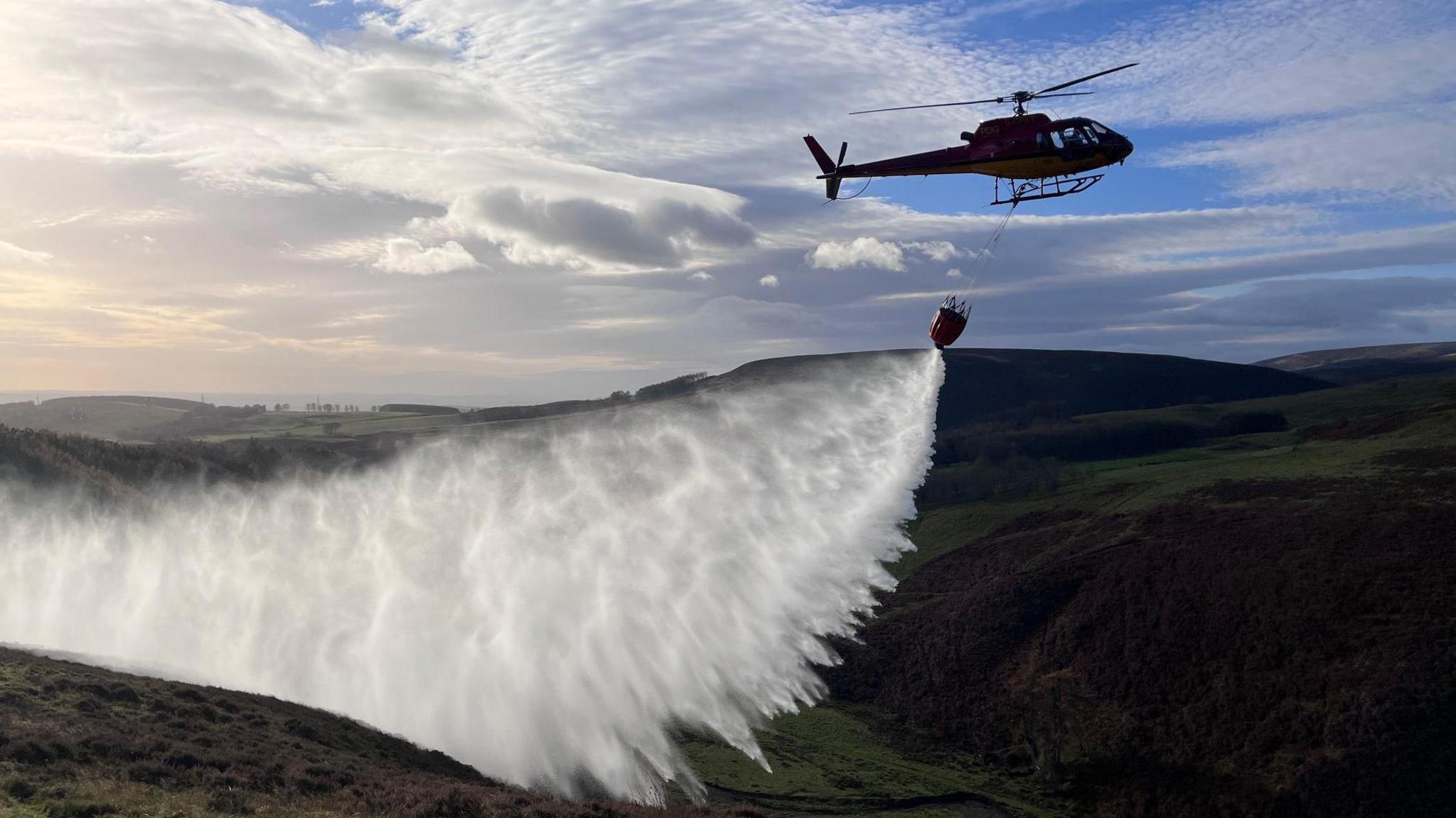 A helicopter demonstrates water bombing on a moorland in Aberdeenshire