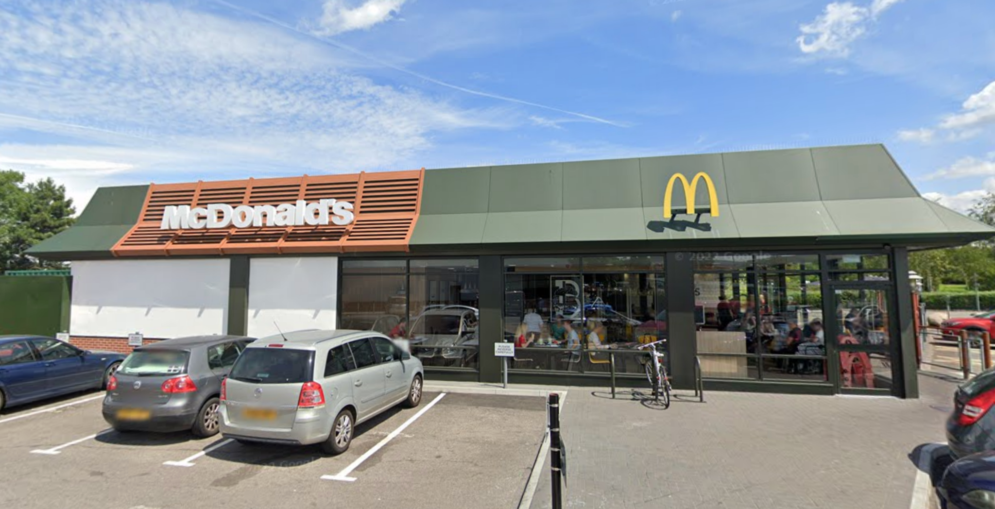 The McDonald's site on Station Road, Filton. Cars are parked within parking bays outside the front of the restaurant. The yellow M is on the roof of the building.