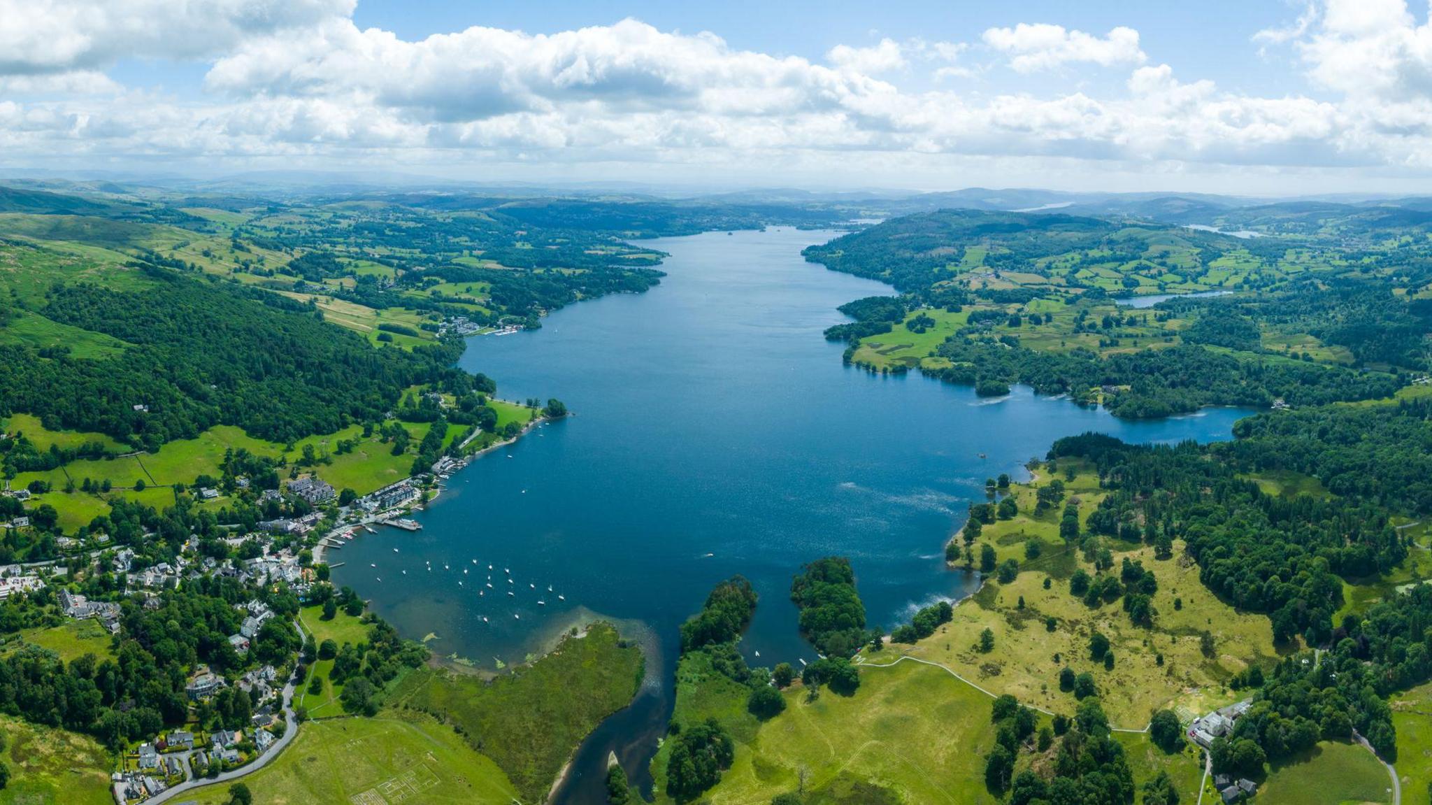 Aerial view of Windermere, a large lake surrounded by trees and fields.