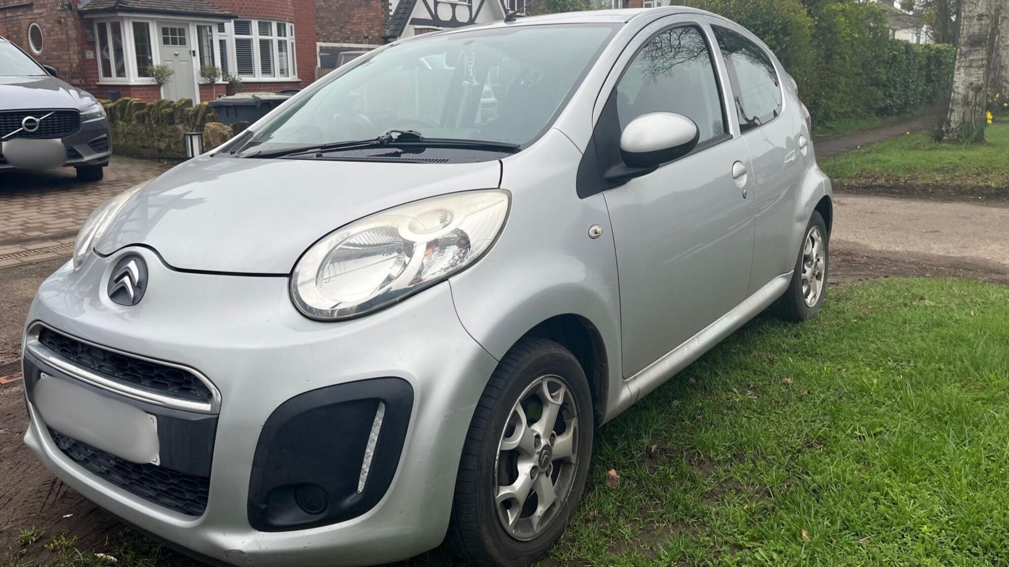 Silver Citroen C1 in front of house.