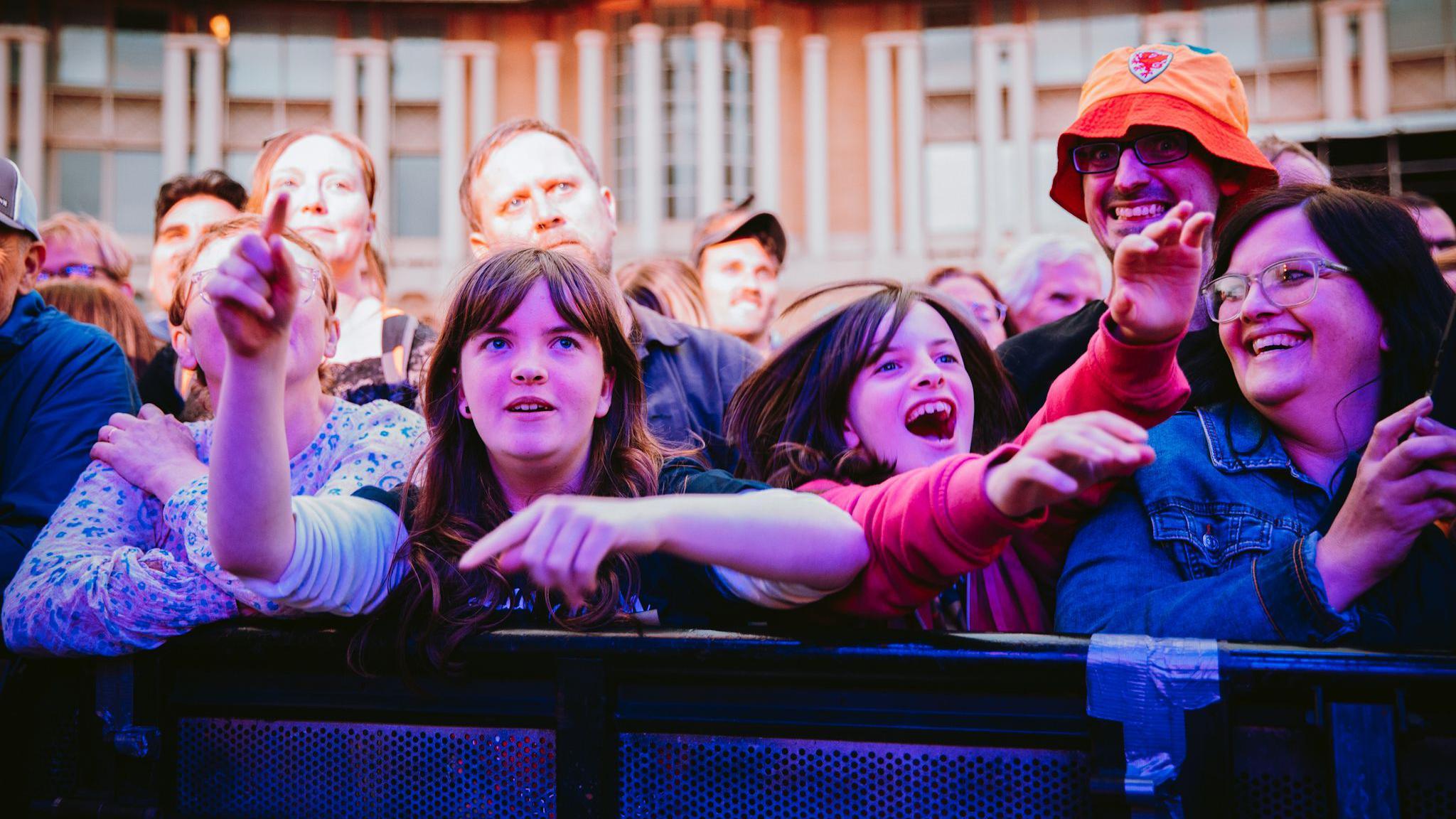 A family enjoy the music from the front of the crowd