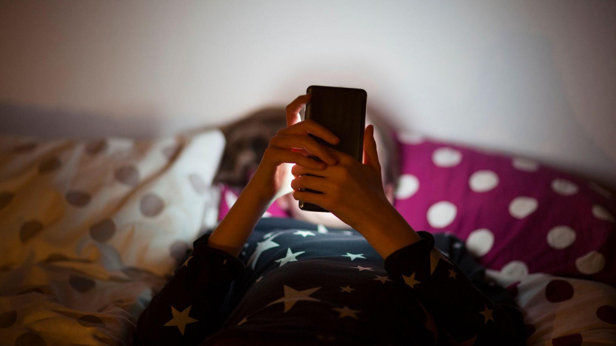 A child scrolls on a mobile phone