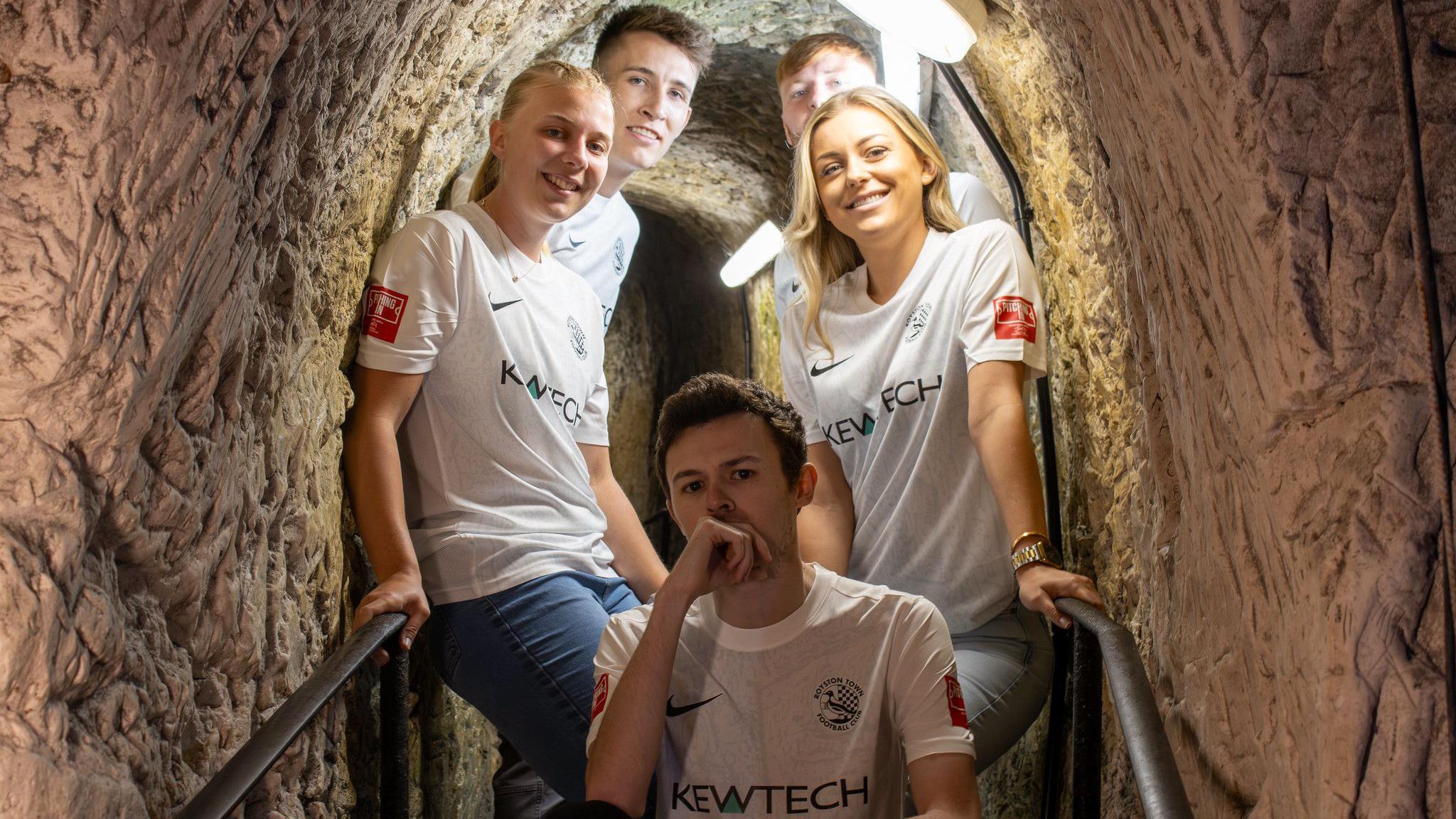 Players in football shirts in a cave scene