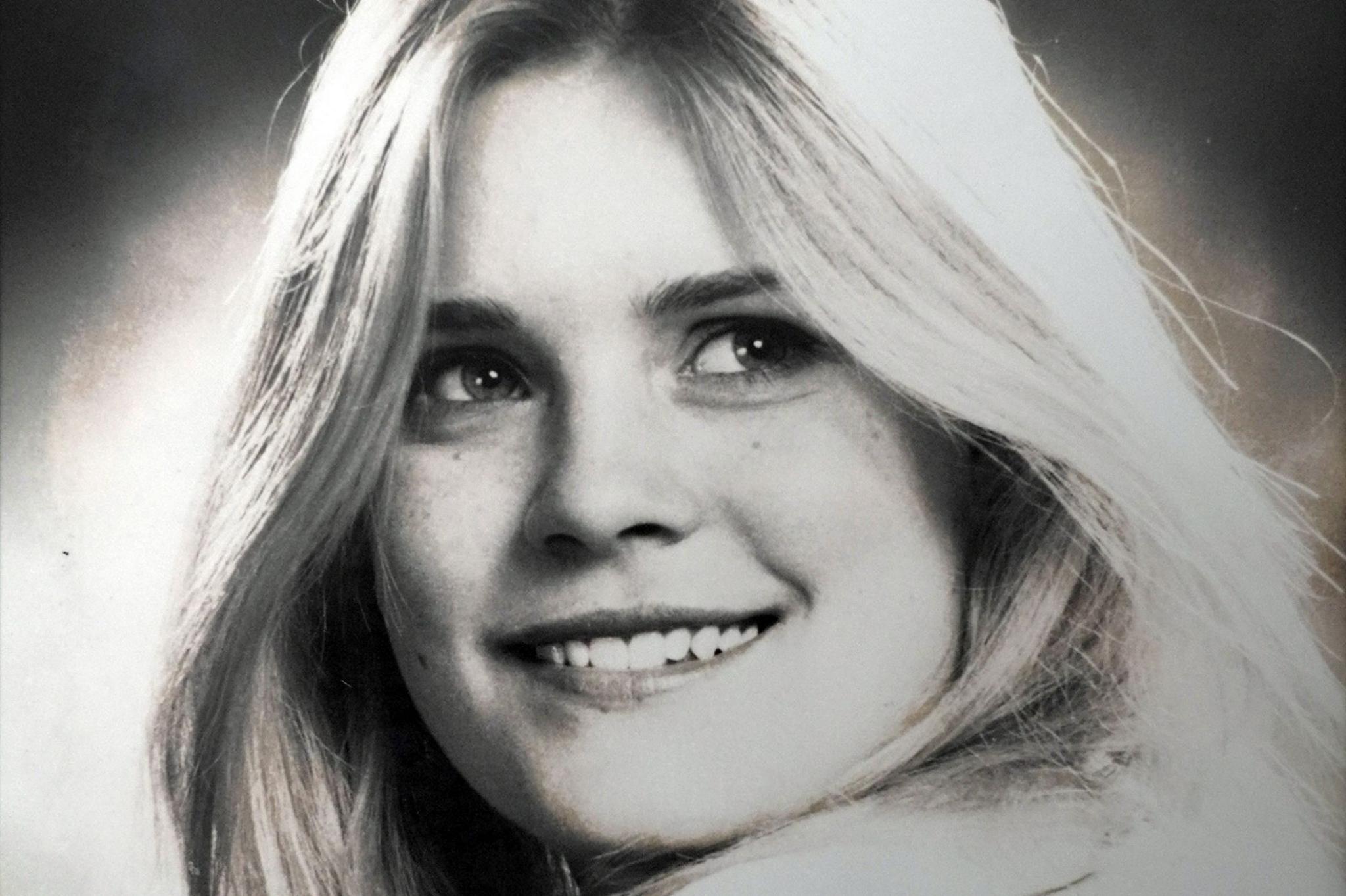 Samantha Ramsay, in a black-and-white studio portrait, with long, fair hair, smiling at the camera