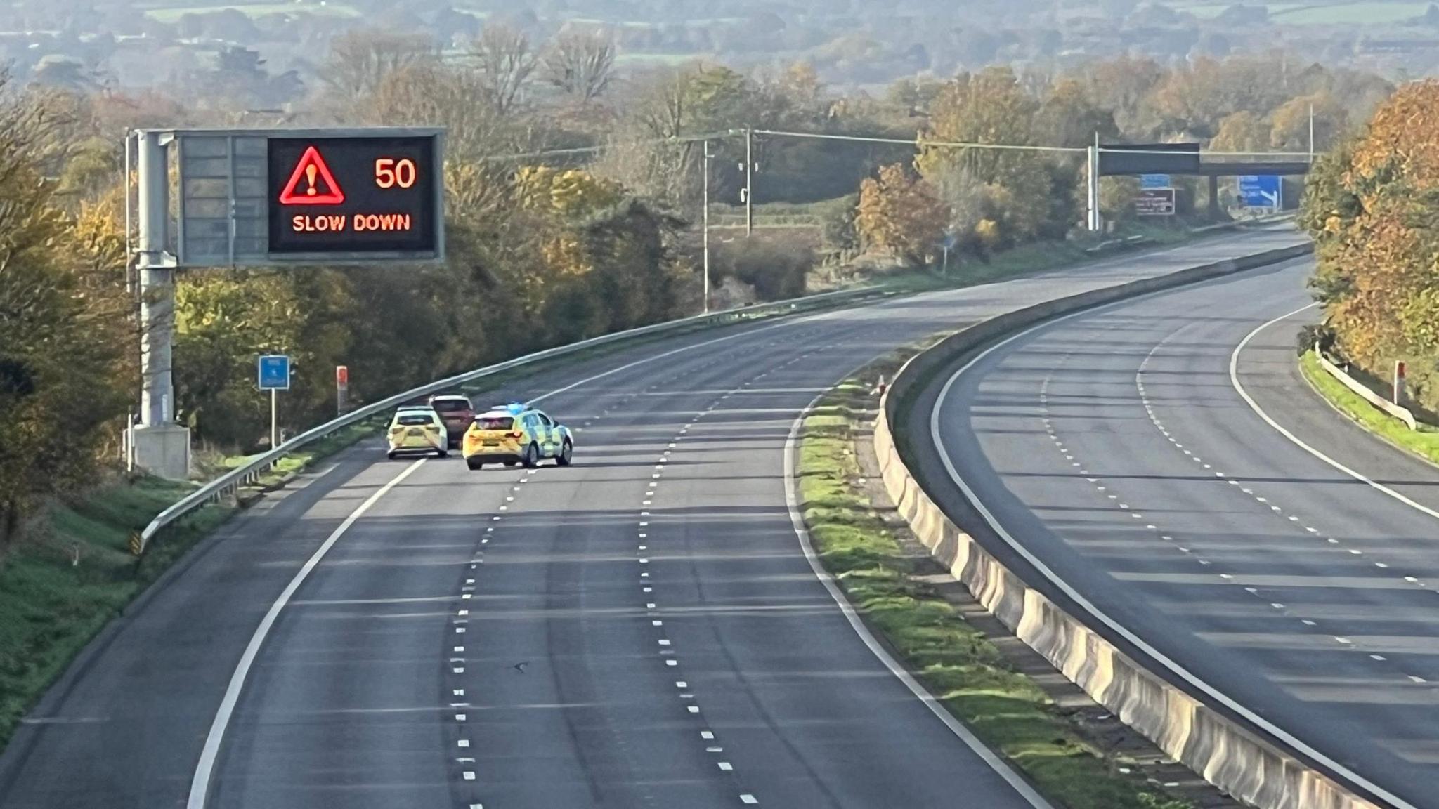 The scene of the crash in M5. Two police cars are on the hard shoulder of the road along with a dark coloured vehicle.