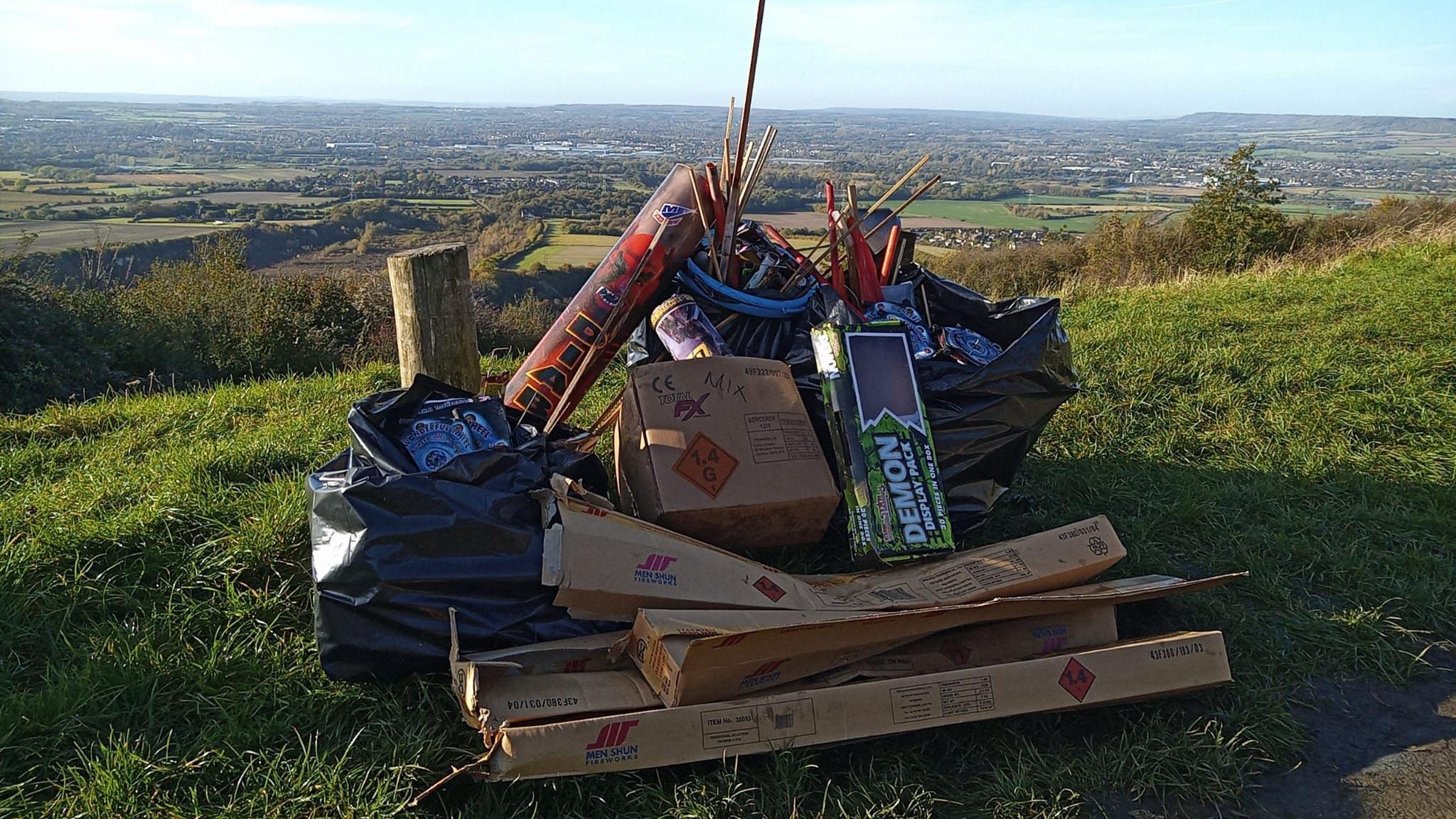 Wooden boxes, litter and bags of rubbish stacked up on a field. 