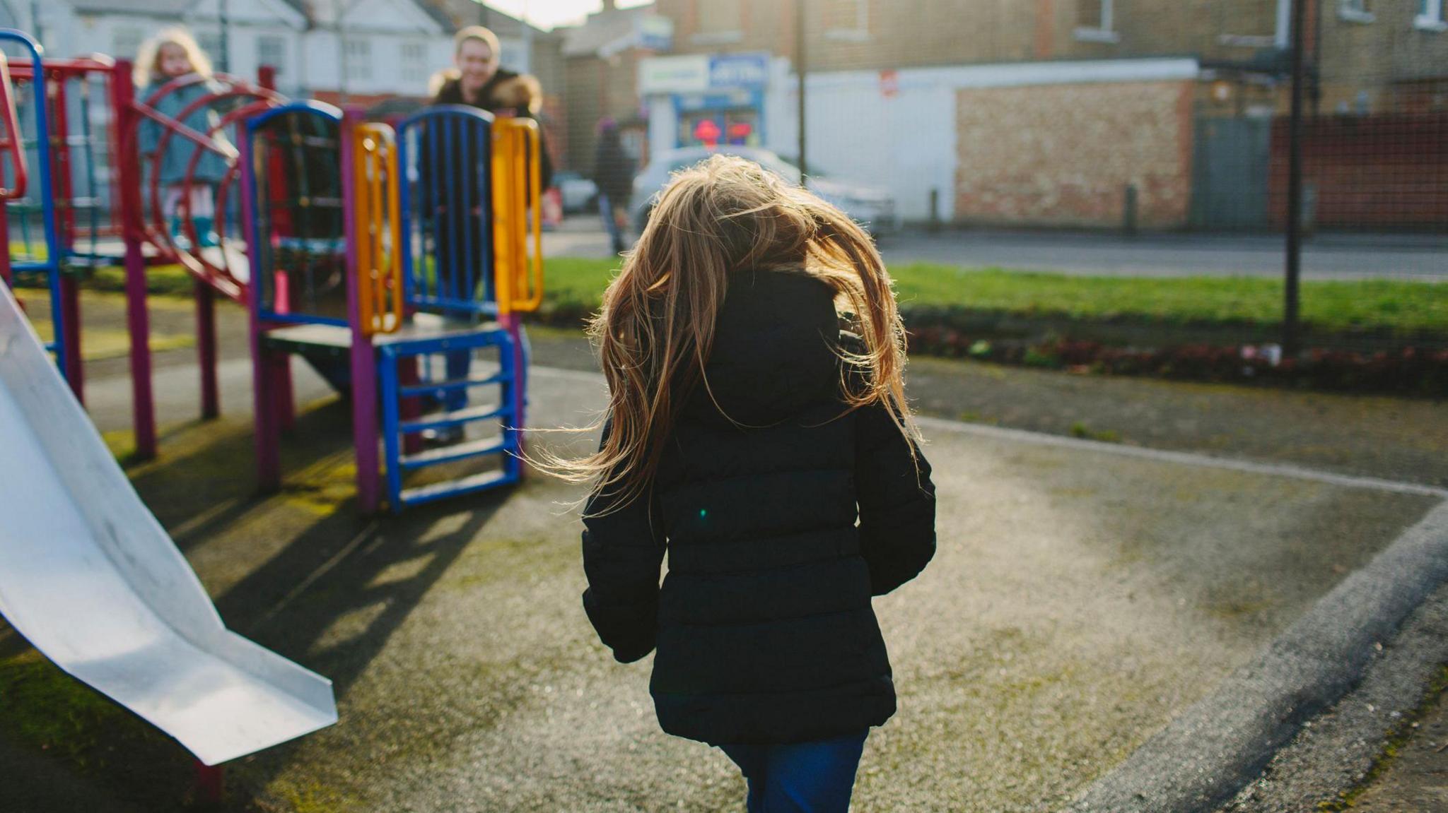 A girl running towards a slide where her friends are