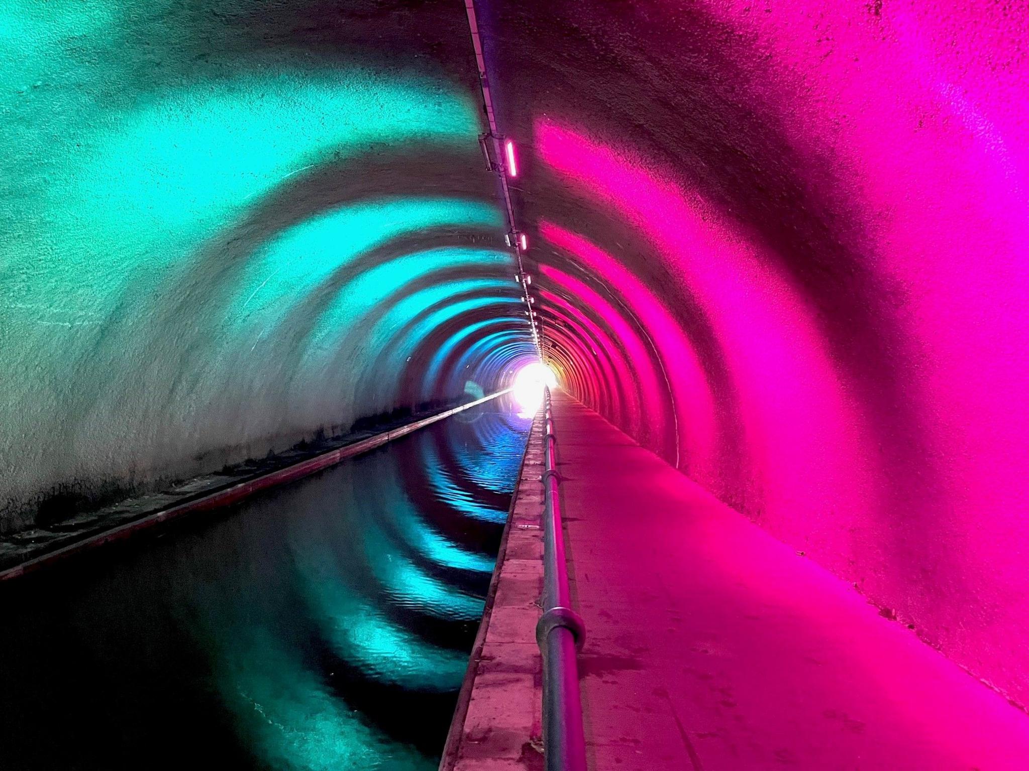 Vivid photo of a tunnel - half blue and half pink - lit by spotlights