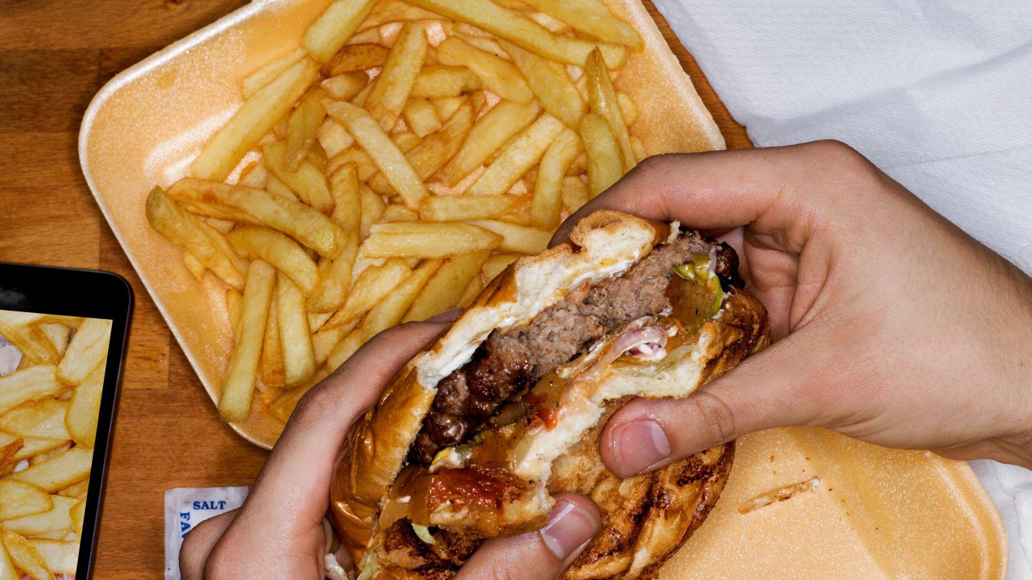 Person eating hamburger and fries