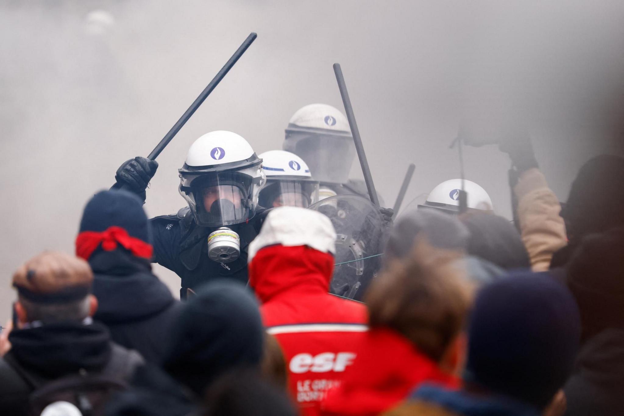 Riot police wield their batons as they confront demonstrator in Brussels, Belgium 
