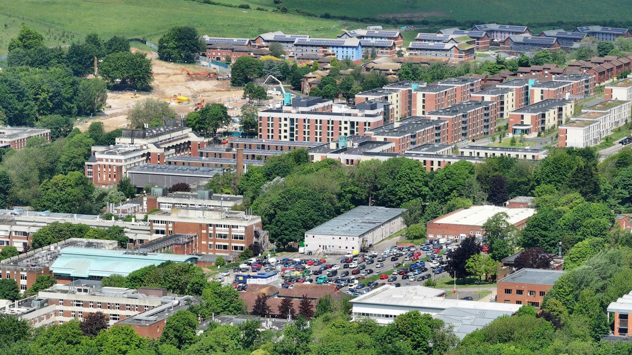 an aerial view of a large complex of university buildings, surrounded by fields and trees