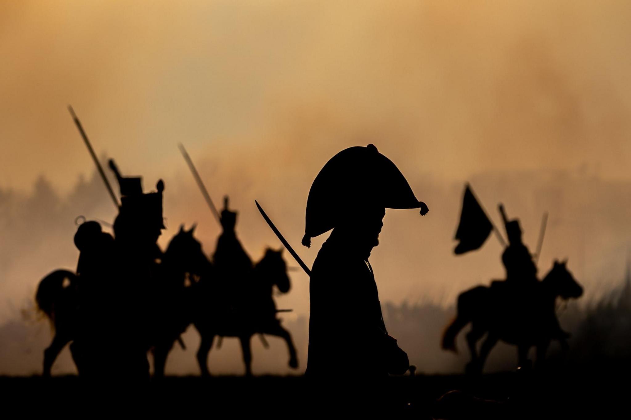 People on horseback are silhouetted against the landscape