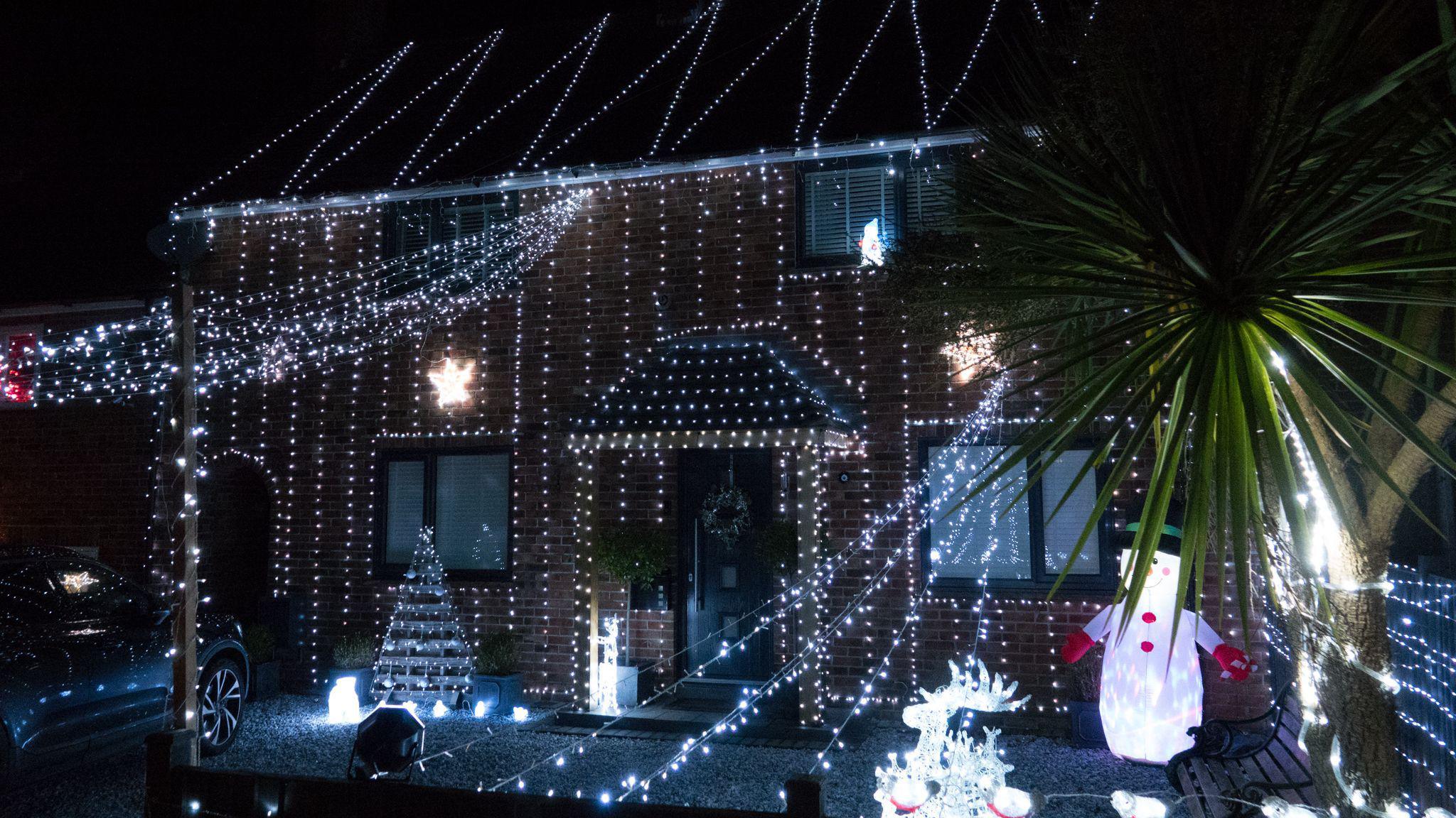 A house covered in lights with a light up snowman out the front