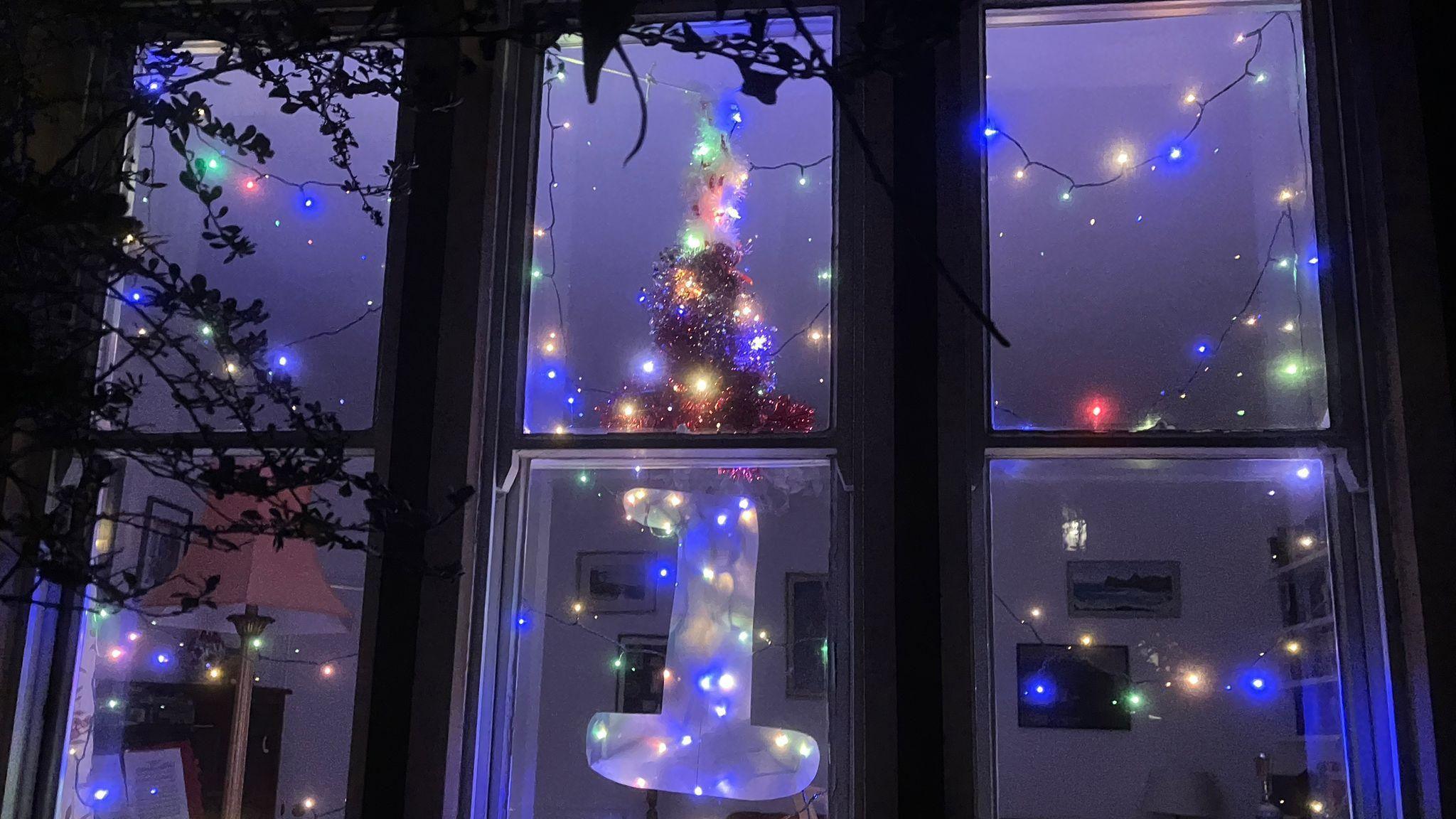 A festive window as part of the Advent trail, with the number 1 and several rows of blue, yellow, green and red Christmas lights.