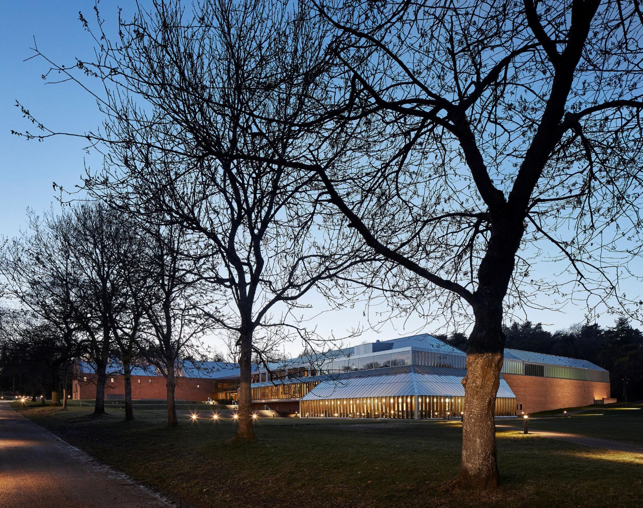 Outside view of the Burrell Collection at dusk, the building lit by warm lights