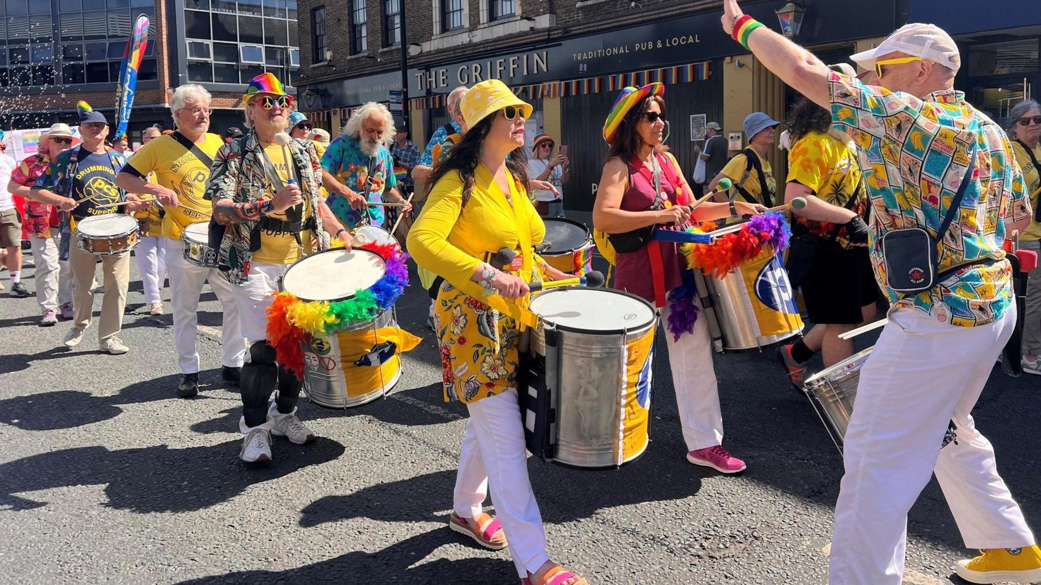 People in yellow tops play drums through the streets of Wakefield. 