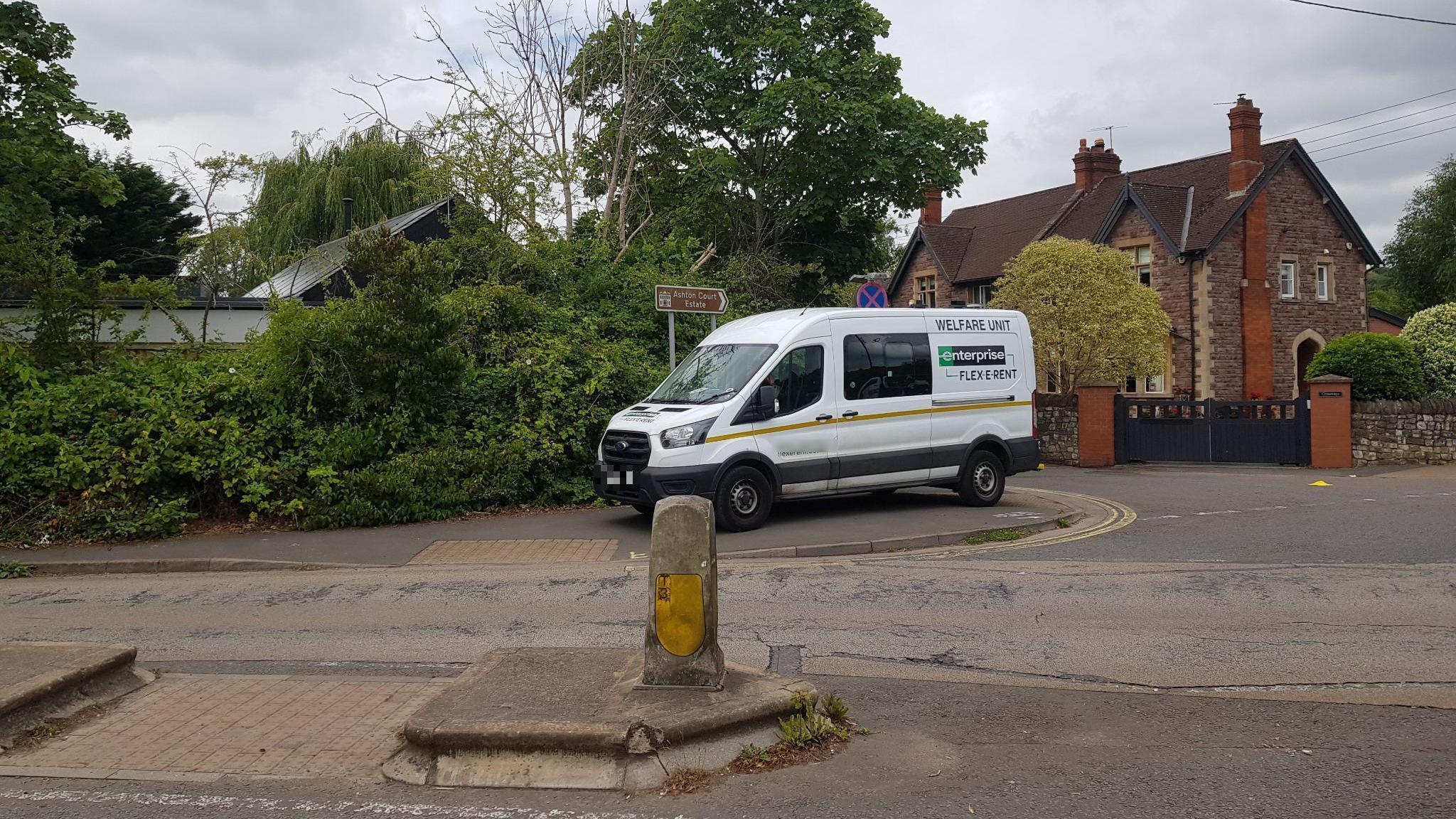 A white rental van parked on a pavement