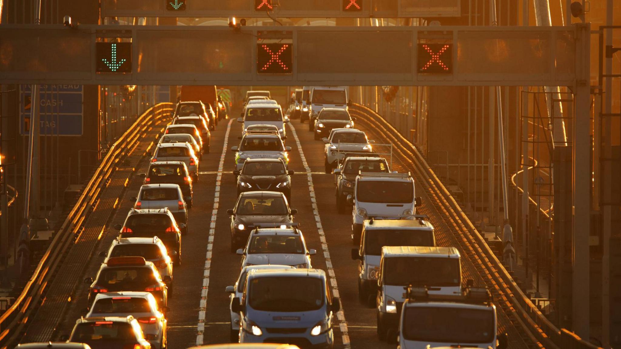 Three lanes of heavy traffic with road indicator signs overhead