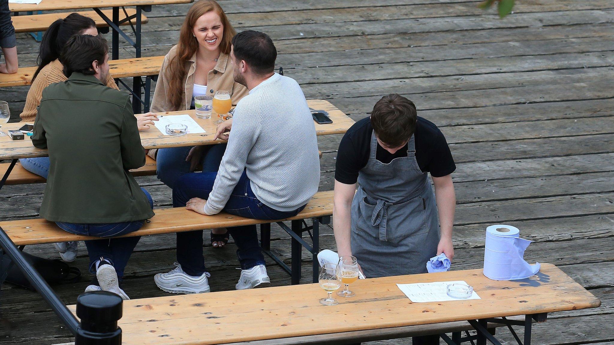 A worker disinfects a recently vacated table outside a re-opened pub in Newcastle