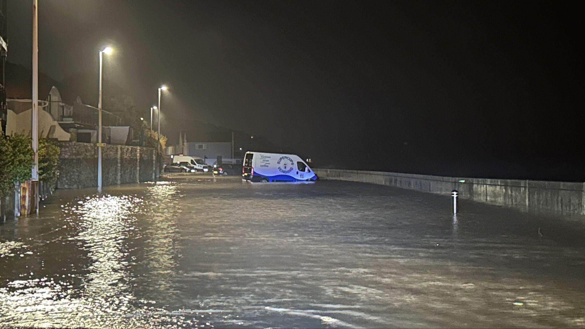 Cars and van seen floating in completely flooded road.