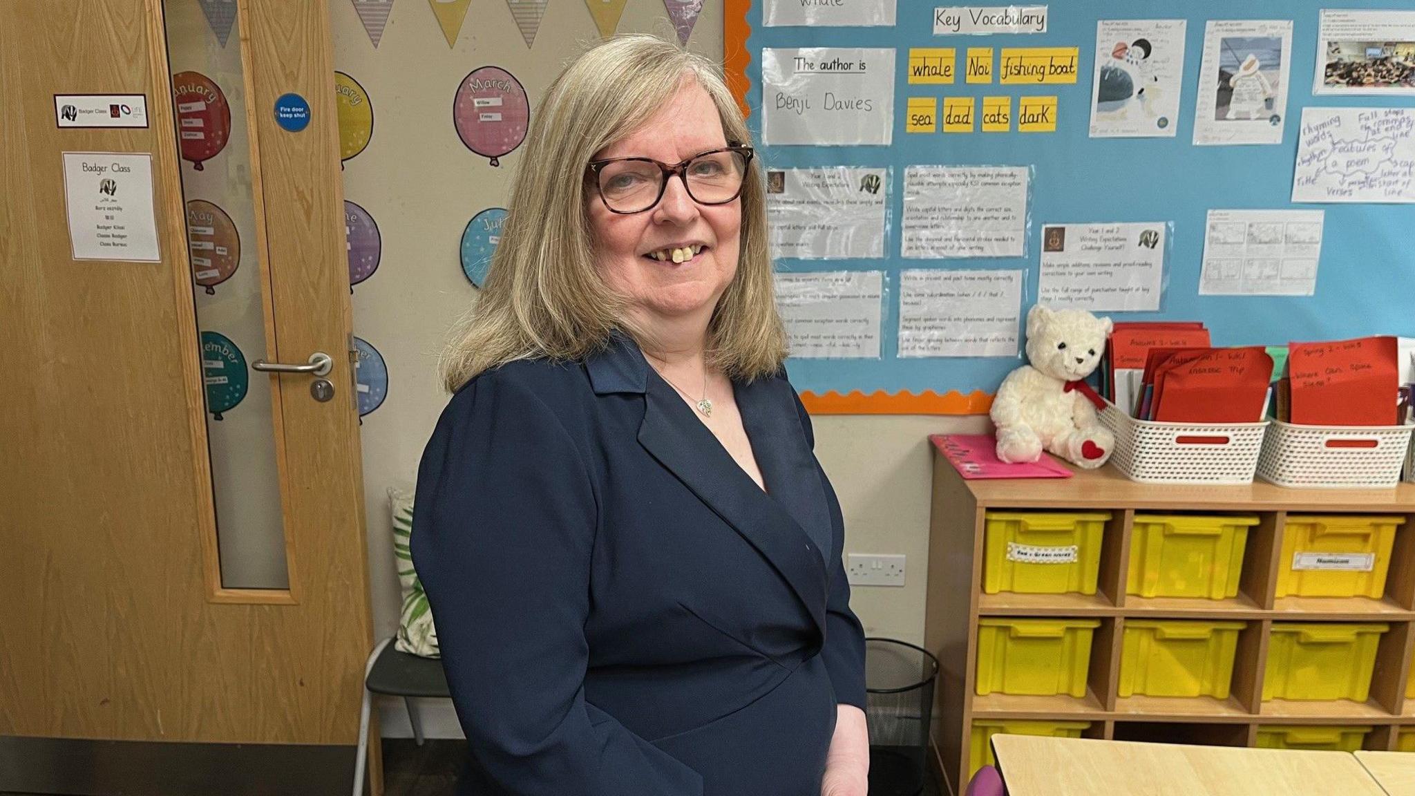 Stella McCarthy  standing in a classroom looking at camera
