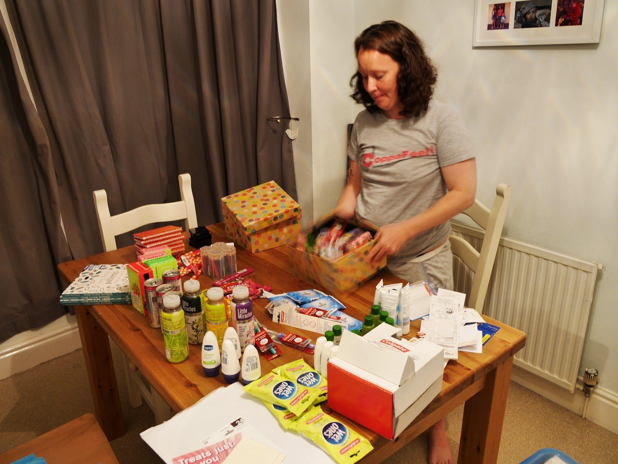 Lisa Wallis packing a box at a table while items to fill multiple boxes sit on the table