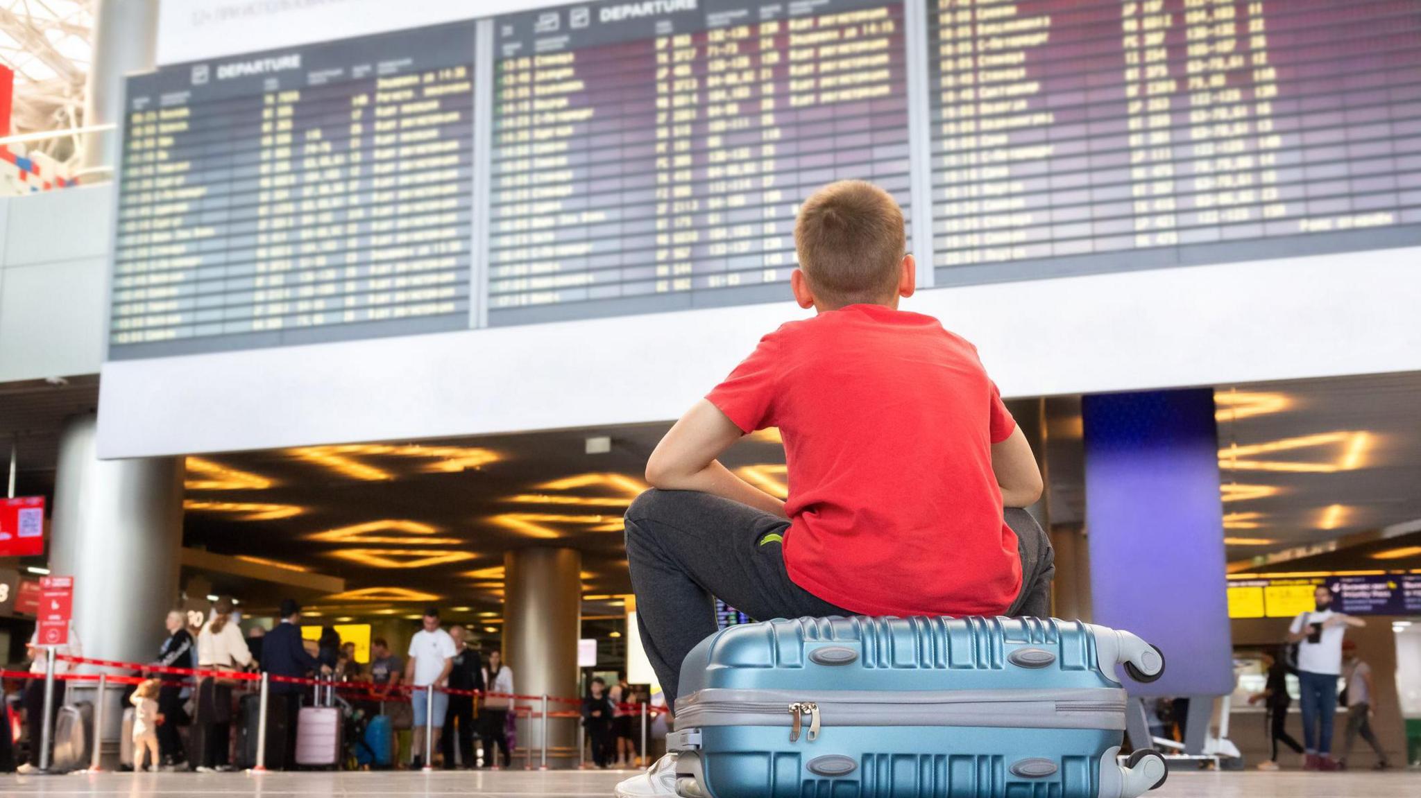 Child sat on suitcase waiting for plane 