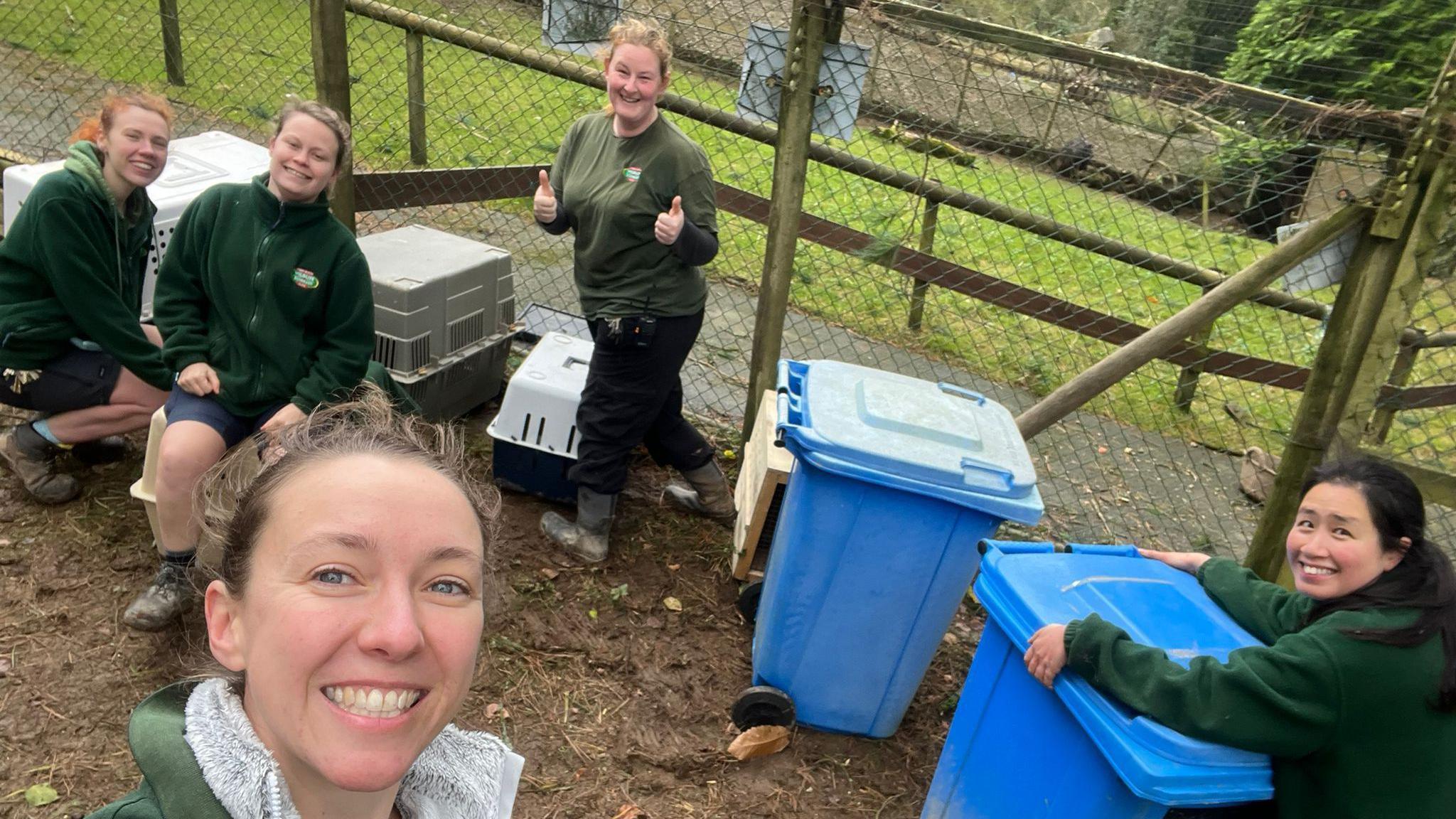 Louisa Bartlett on the left taking a selfie with her team members. There are three members of staff on the left, behind her, with crates and another member of staff on the right holding the lid of a blue wheelie bin down.