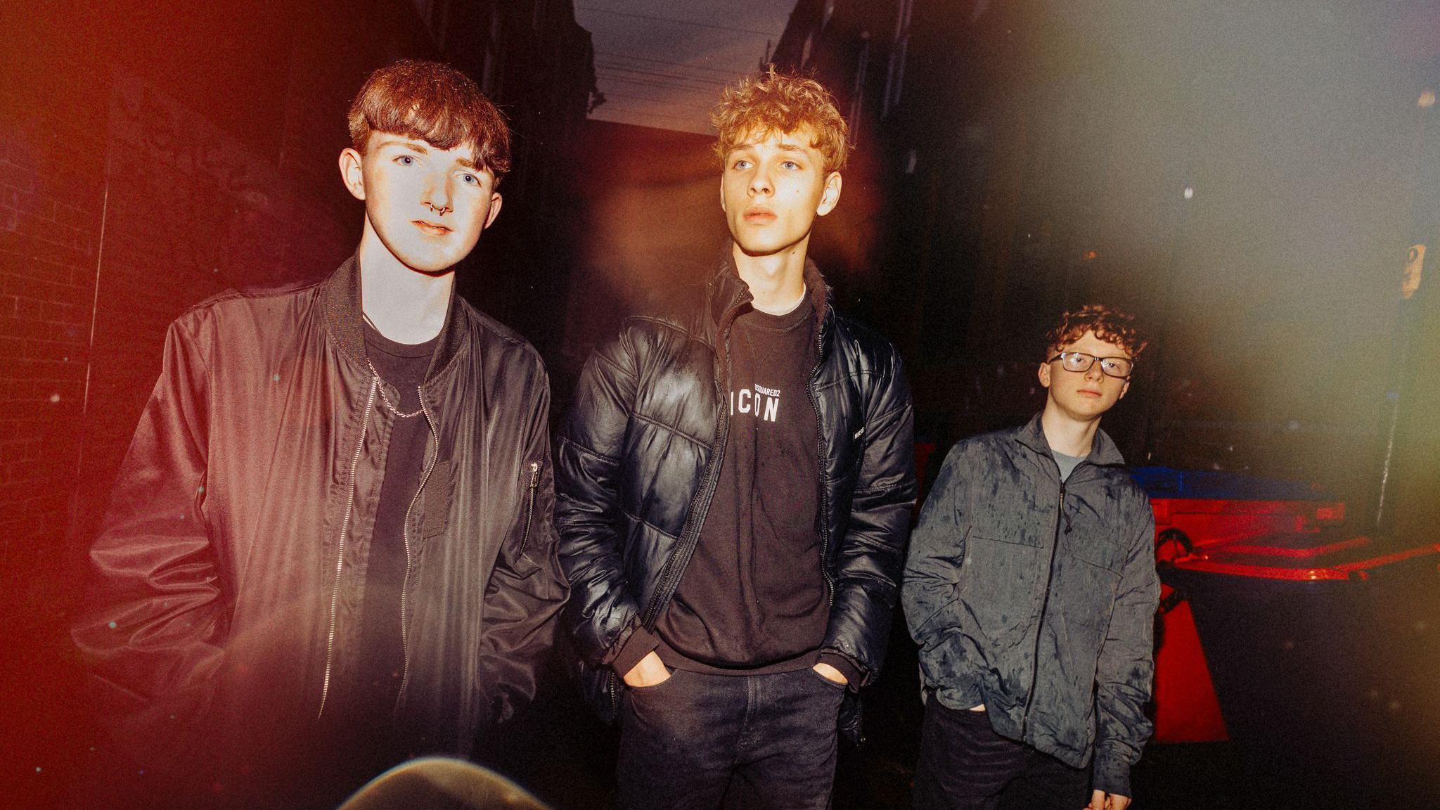 Musicians Josh, Ben and Lewis who play as Revivalry. They are photographed in high contrast,  walking down a street in the dark while wearing dark jackets.