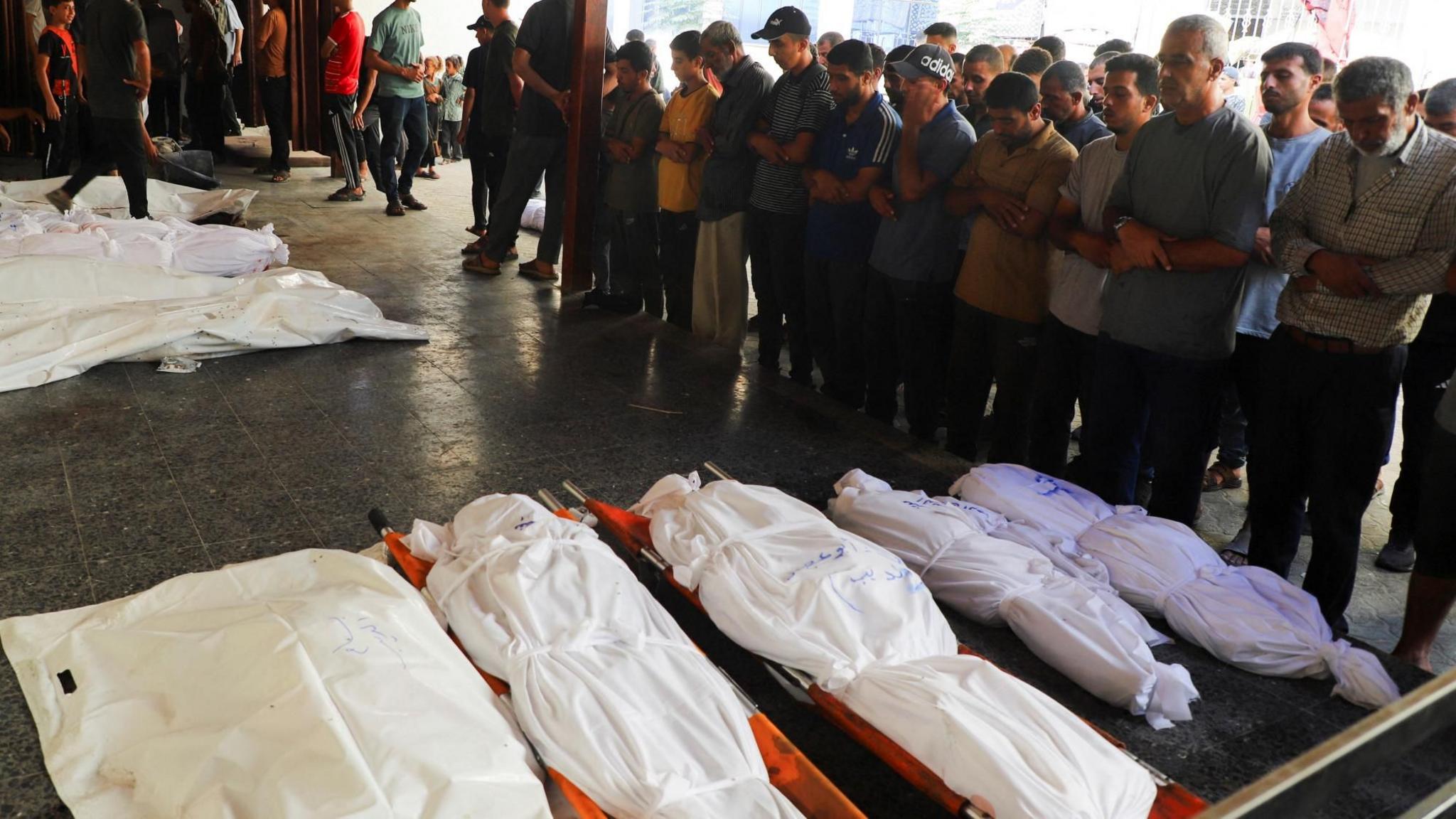 Mourners pray near the bodies of people reportedly killed in an Israeli air strike on a building where displaced families were sheltering, at al-Ahli hospital, Gaza City (24 September 2025)
