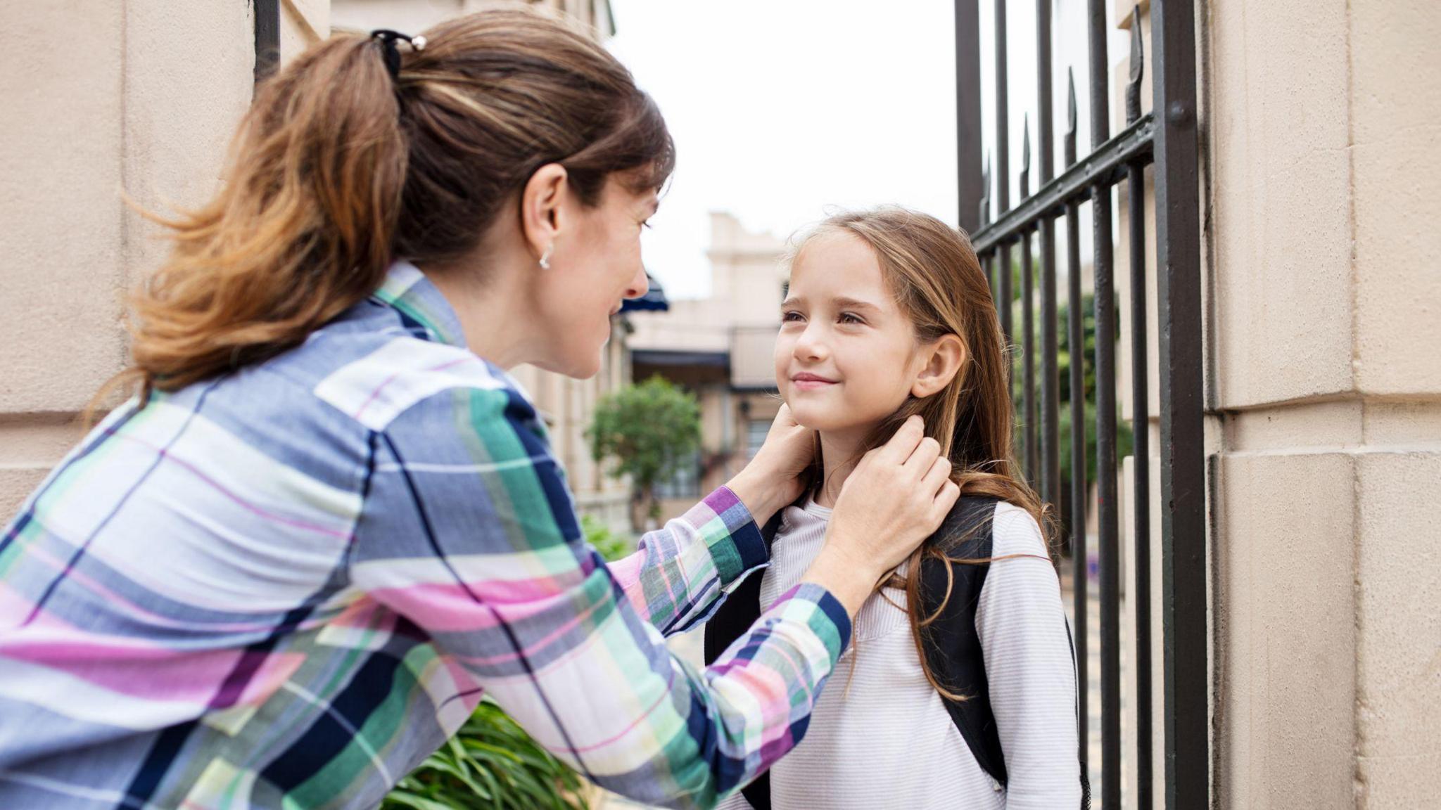 girl-outside-school-gate-with-mum. 