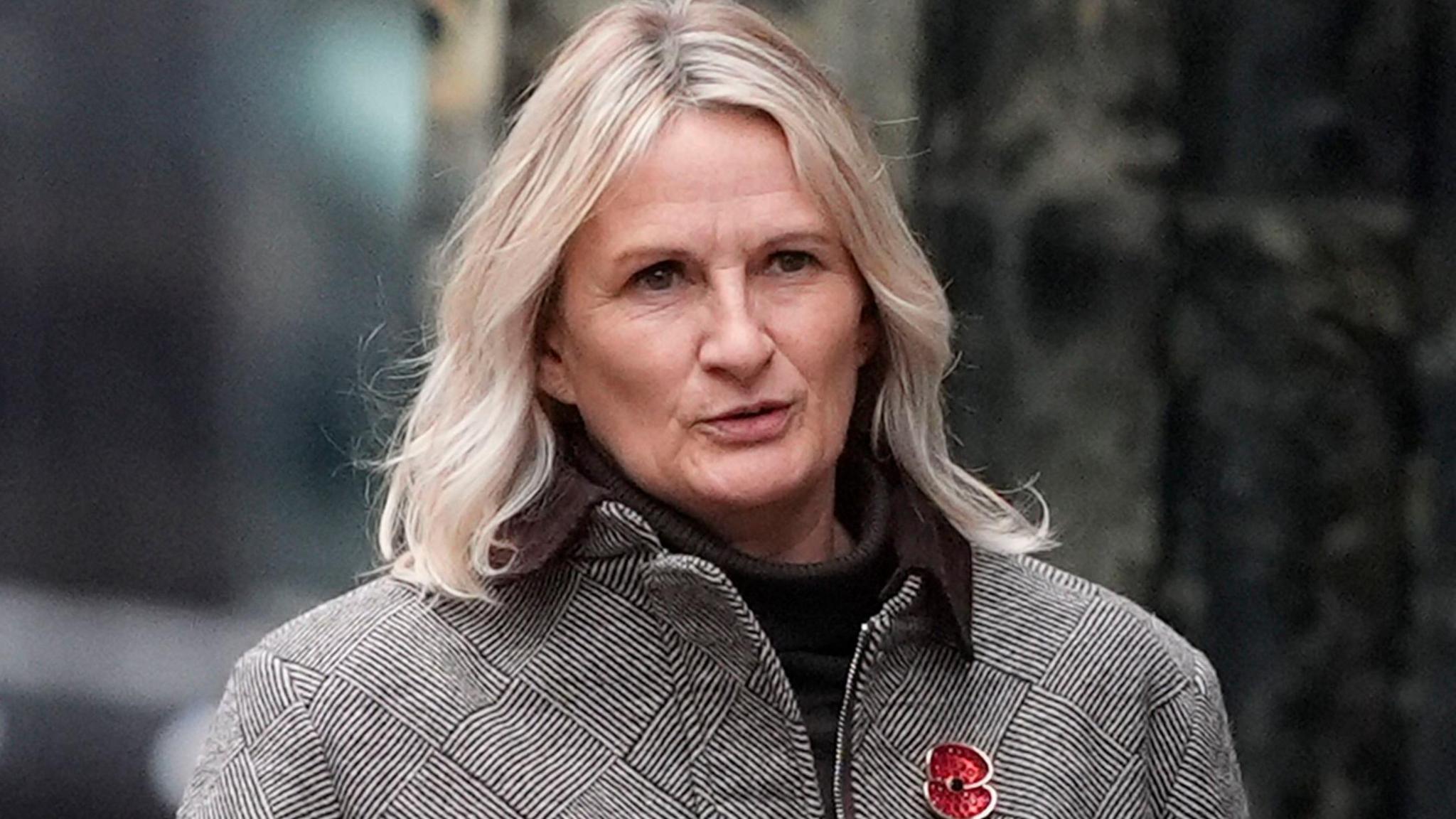 Lucy Ward with blond bobbed hair arrives at Liverpool Crown Court wearing a dog tooth patterned jacket and black roll neck jumper.
