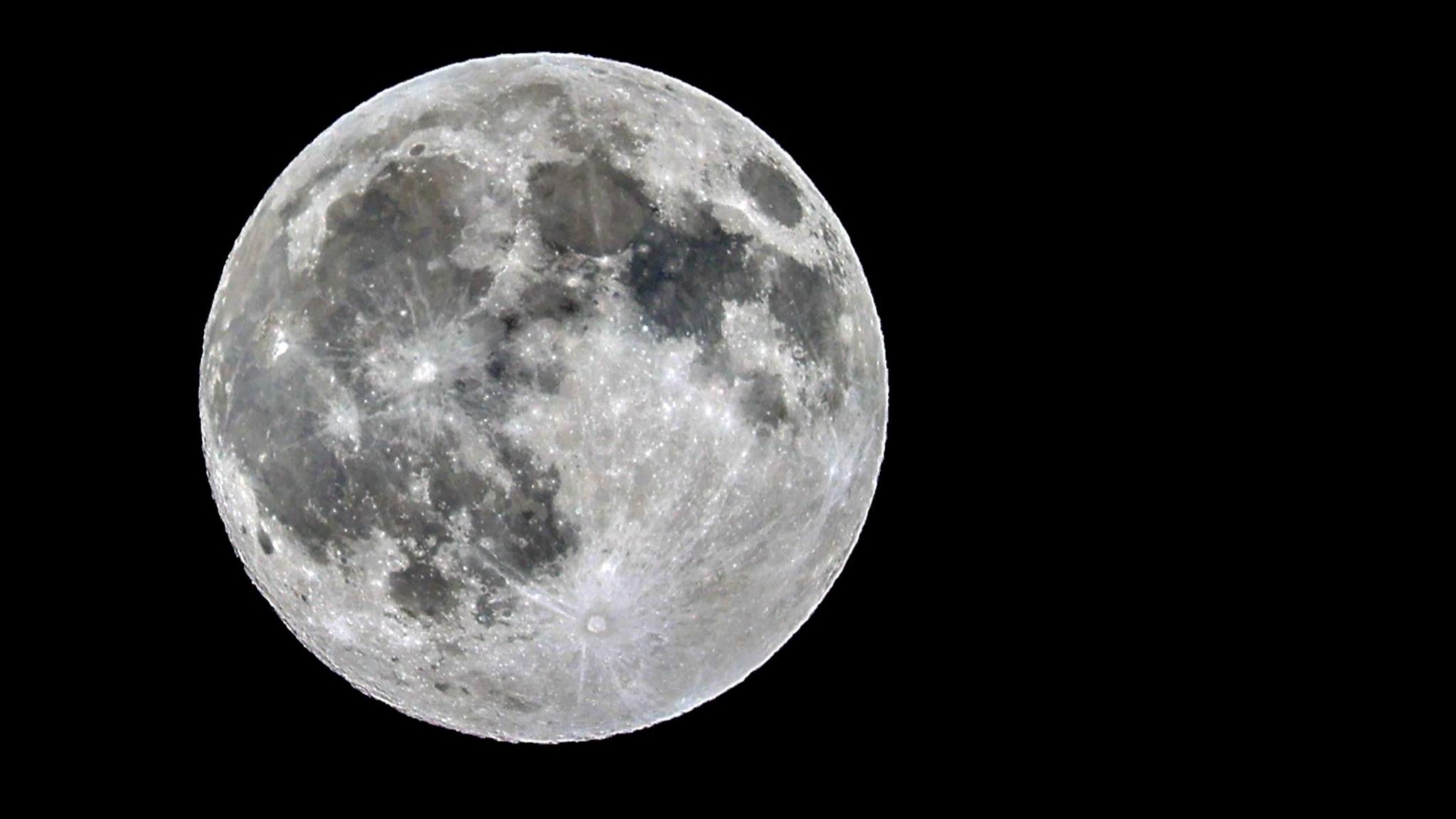 Close up of silver supermoon with visible craters in a black sky