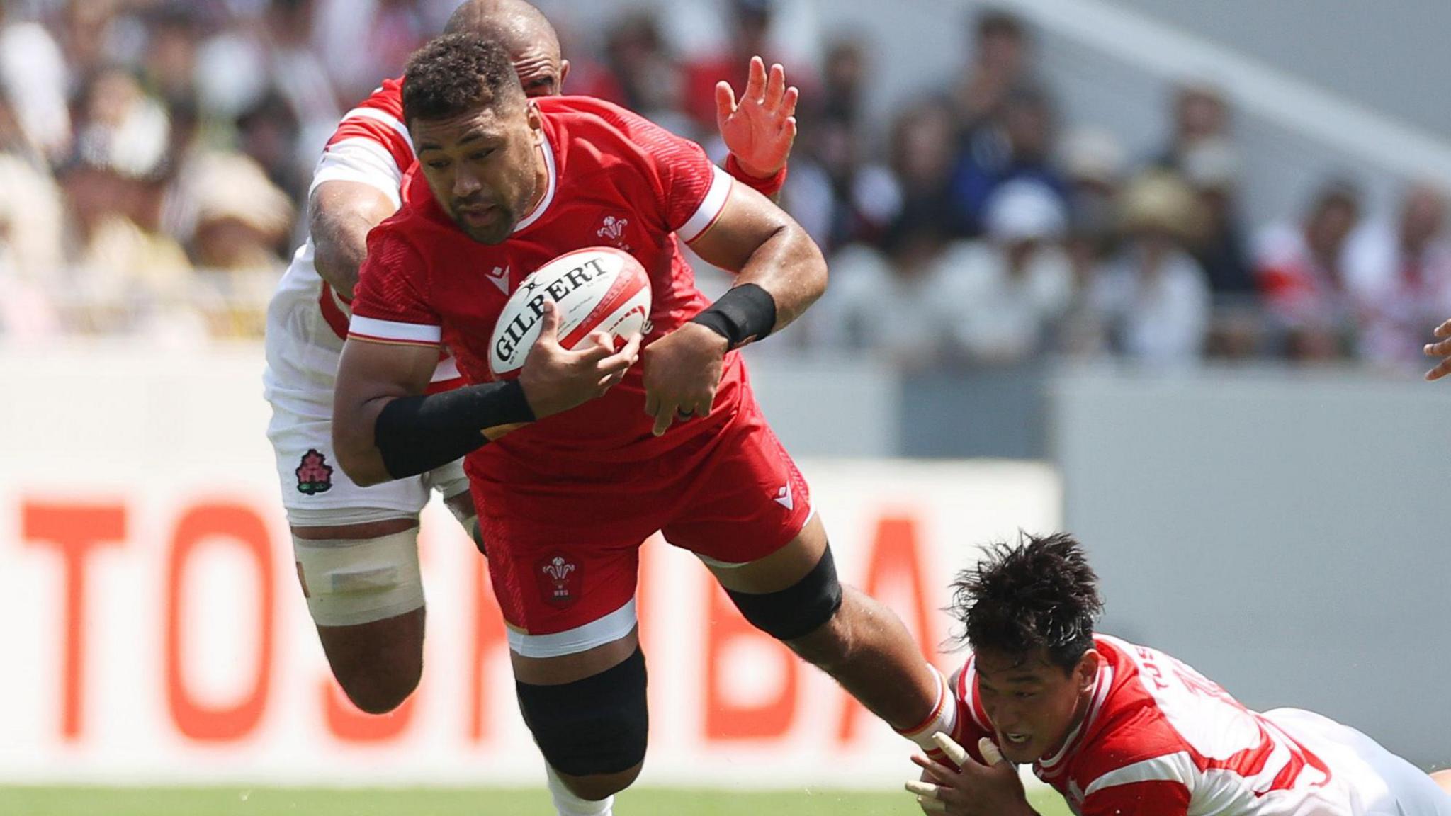 Taulupe Faletau is tackled by two Japan defenders