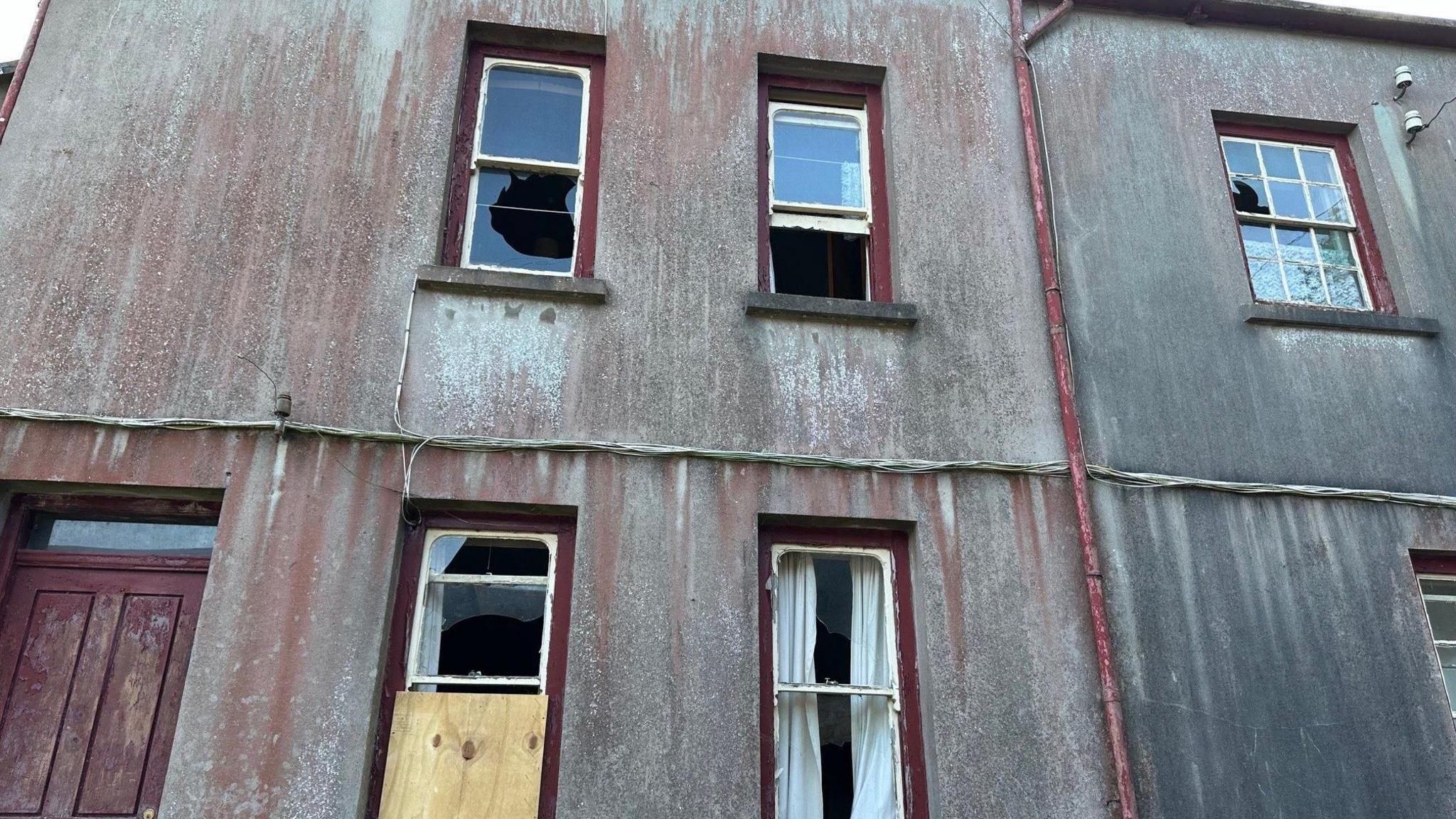 A section of the farmhouse with windows smashed