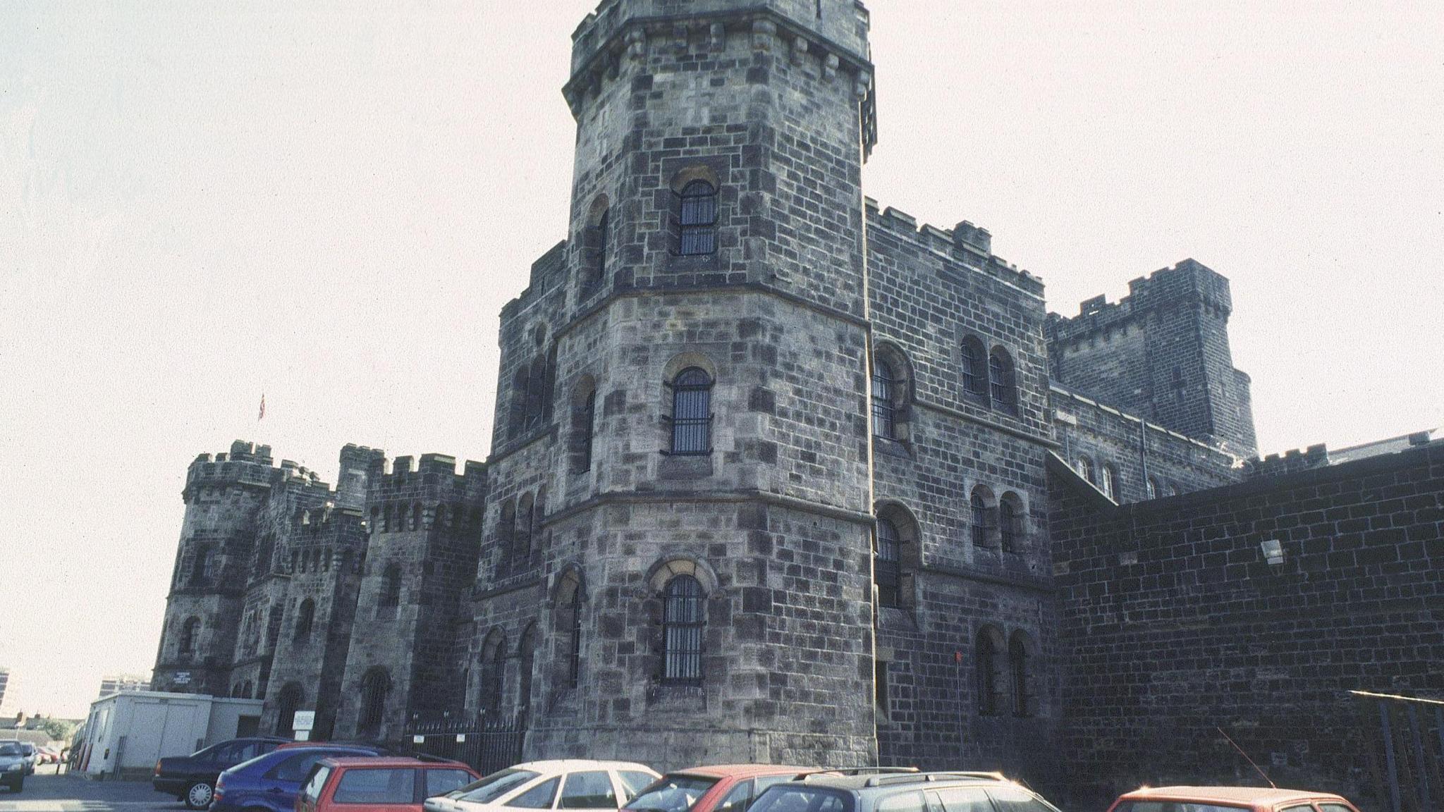 A castellated Victorian building with cars parked outside