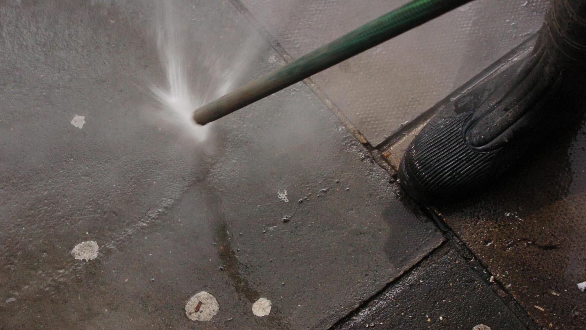 A council worker uses a gum buster to remove chewing gum from a pavement.