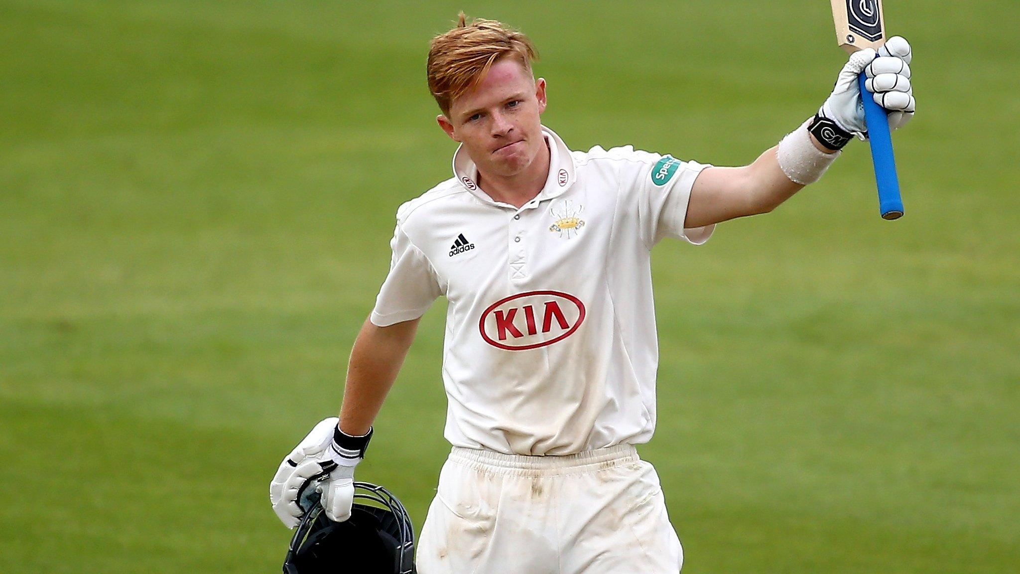 Ollie Pope raises his bat in his left hand in celebration after making a century against Yorkshire