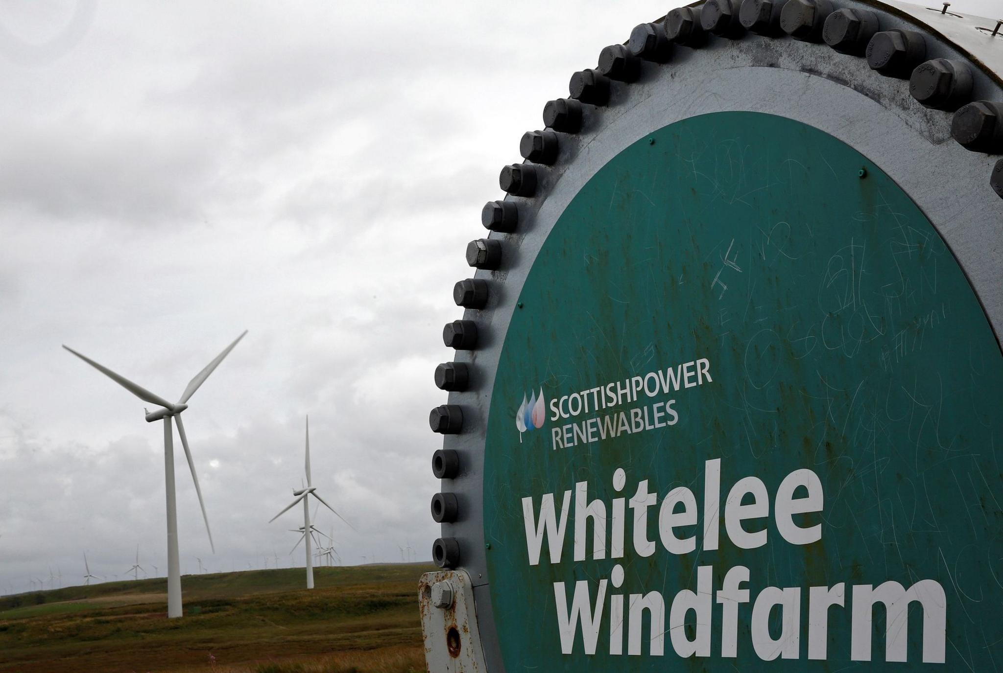 A sign for Whitelee Windfarm with turbines in the background.