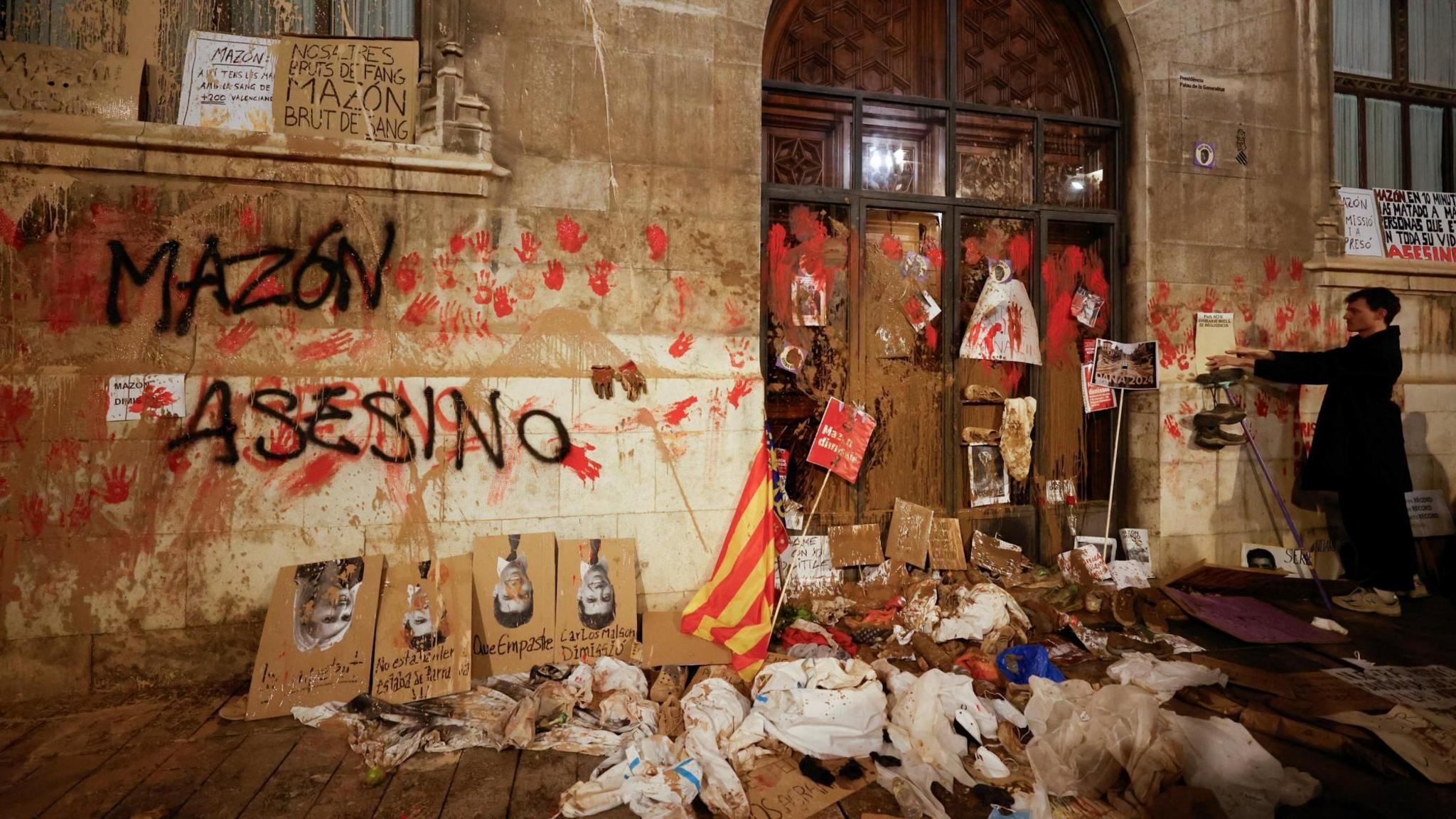 A person stands in front of Valencia's Regional Government Palace, which is stained with mud and paint, during a protest against Valencia's regional leader Carlos Mazon and the management of the emergency response to the deadly floods in eastern Spain, in Valencia, Spain,