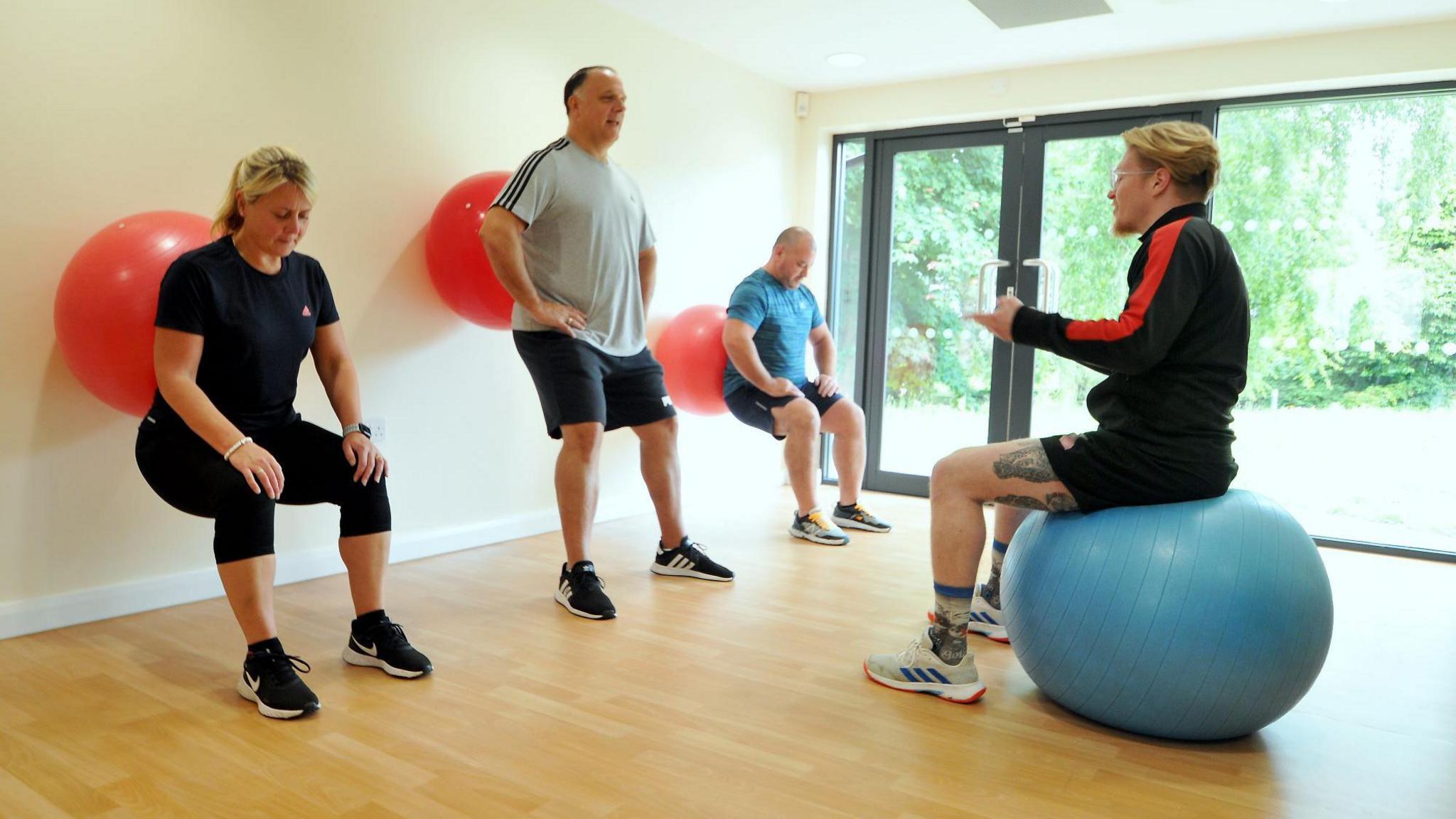 Two men and a woman do pilates with exercise balls