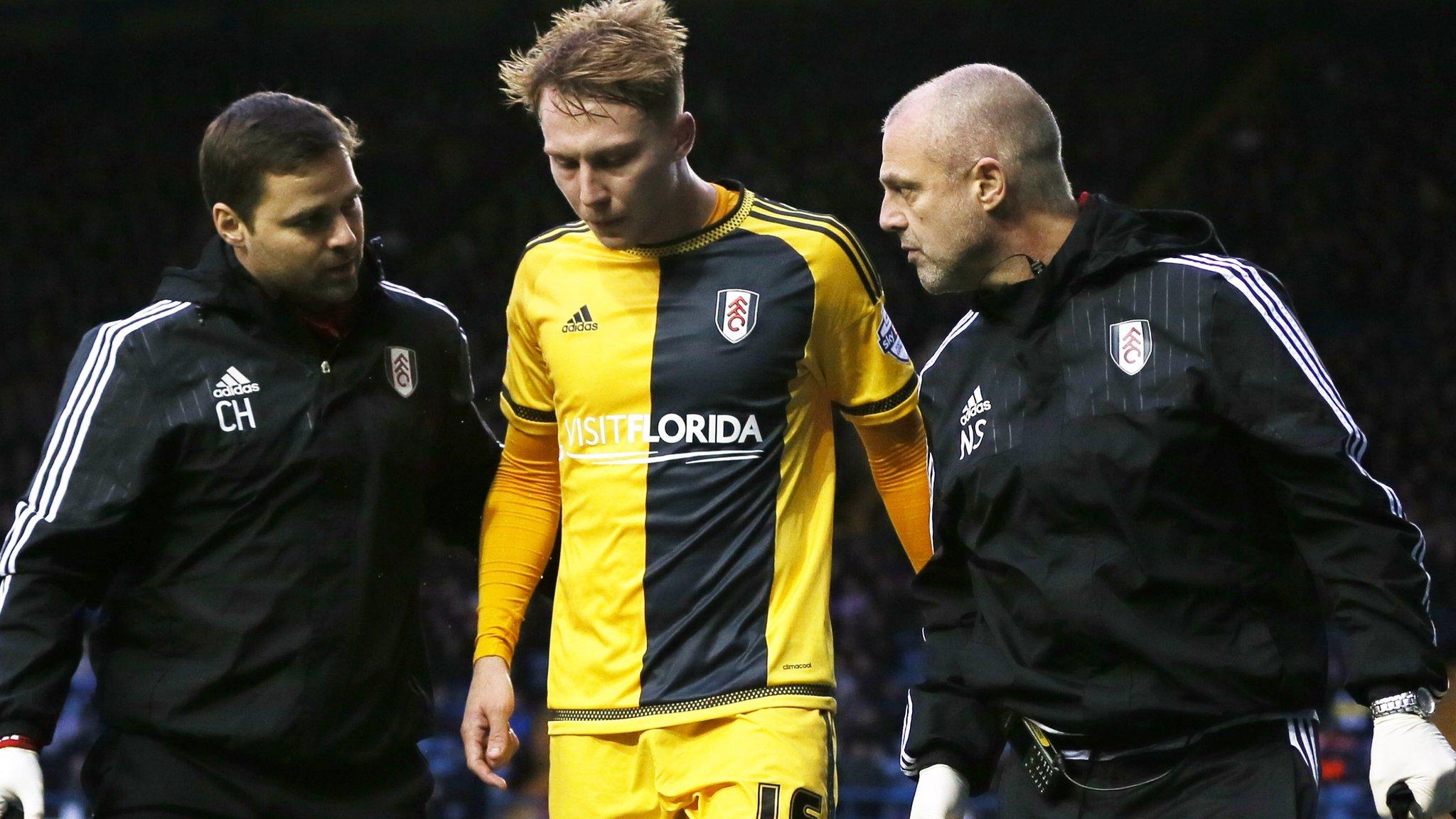 Fulham's Cauley Woodrow limps off the field with the help of the club's medical staff