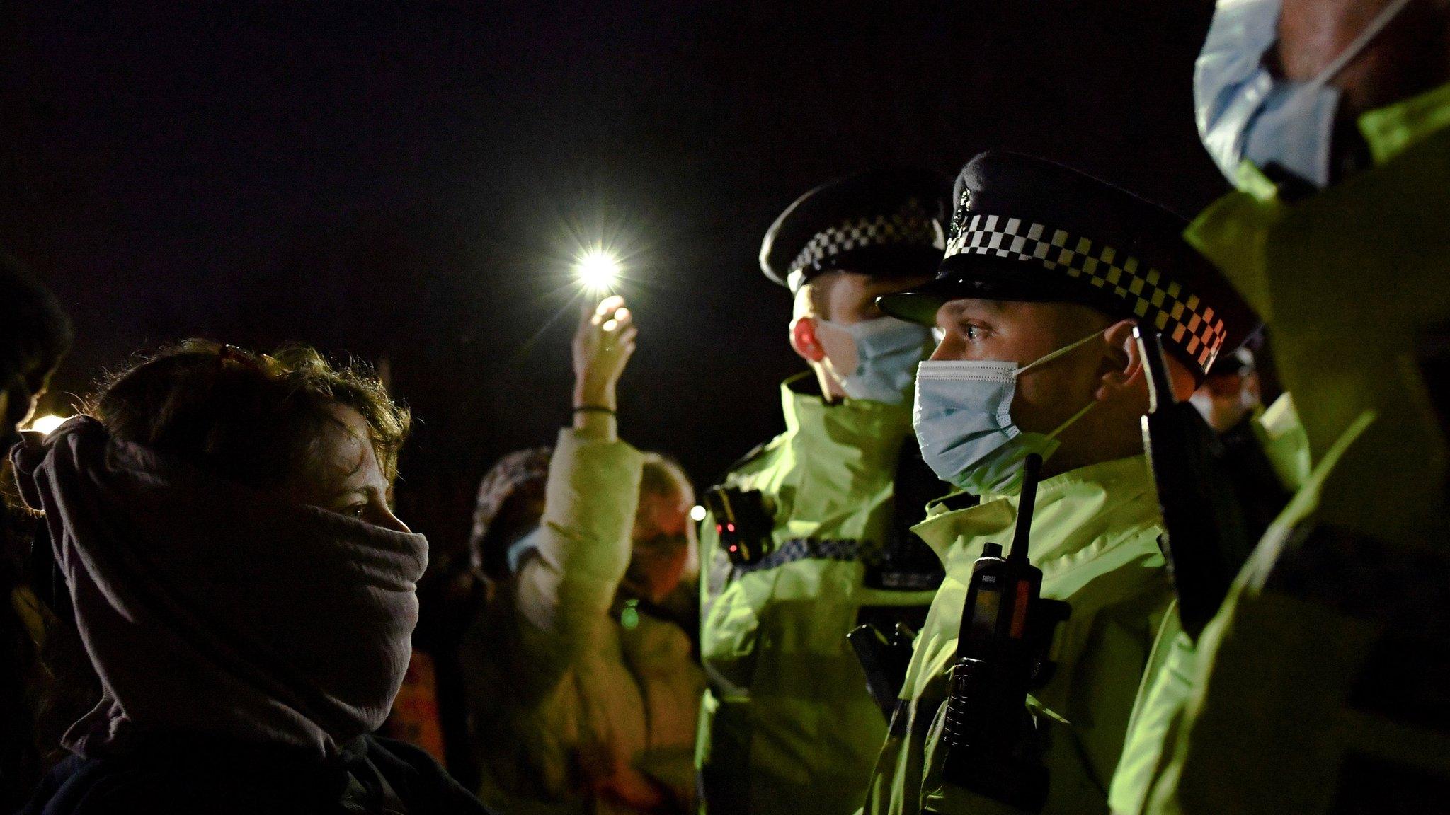 Mourners face police officers at a memorial site at the Clapham Common Bandstand