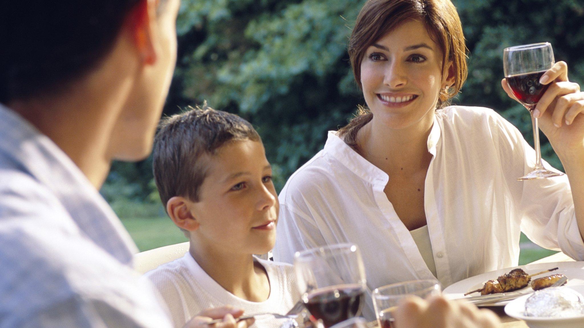 A couple drinking wine, sat with a young boy