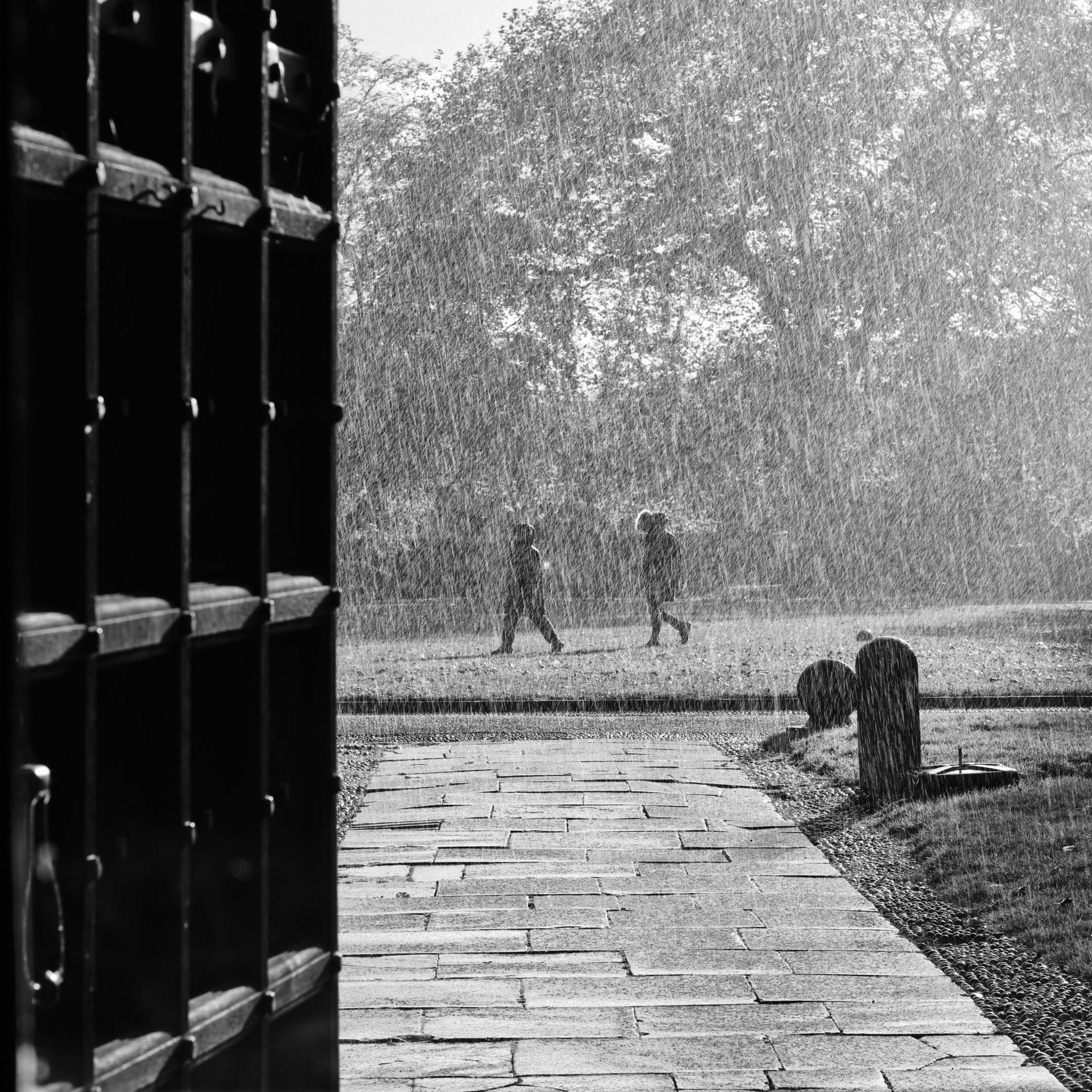 Two people walk through the rain