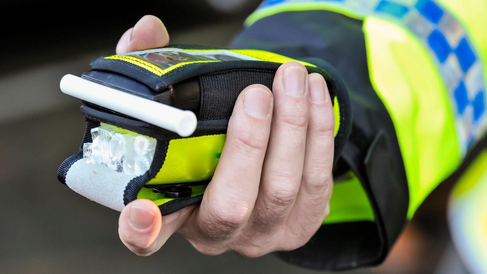 A police officer holds a roadside breathalyser alcohol breath test after taking a sample from a driver