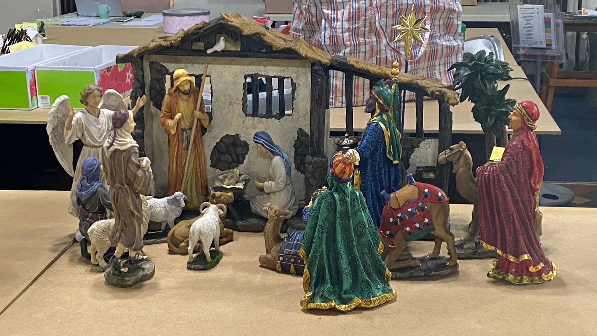 A ceramic nativity scene. The stable where Jesus was born can be seen, full of figures including an angel, Joseph, Mary and sheep. 