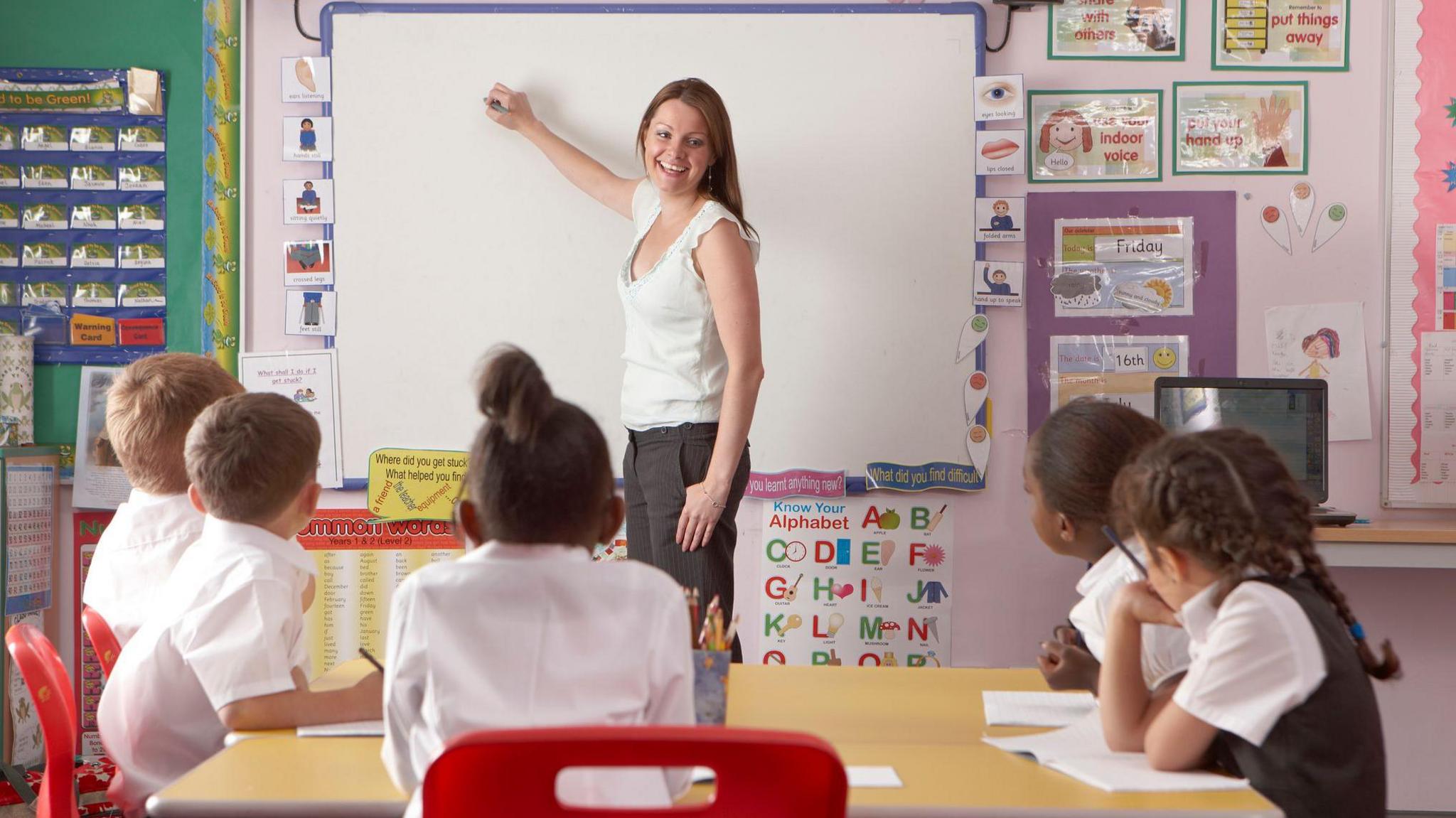 Teacher standing at a whiteboard teaching a class