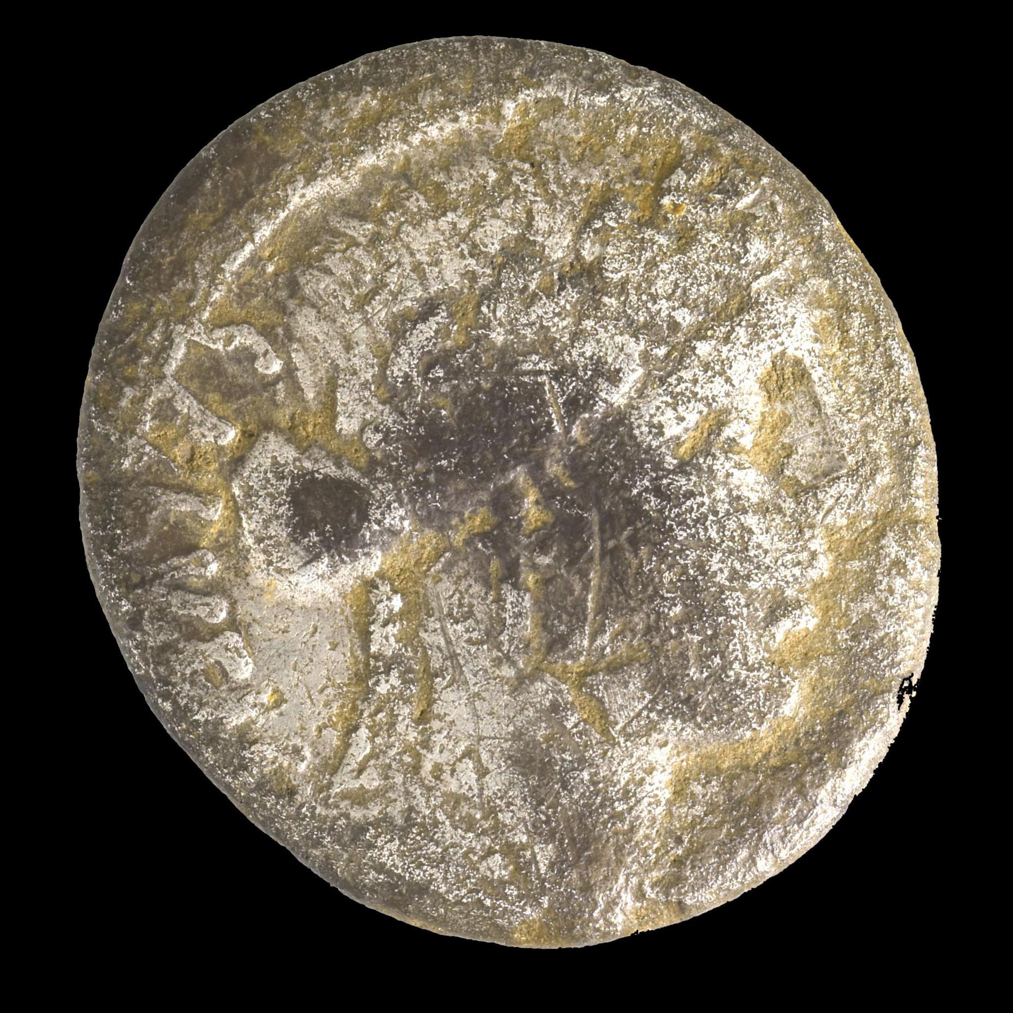 A round Roman coin - it is not perfectly round but has uneven edges.  A pattern can be seen on its surface.