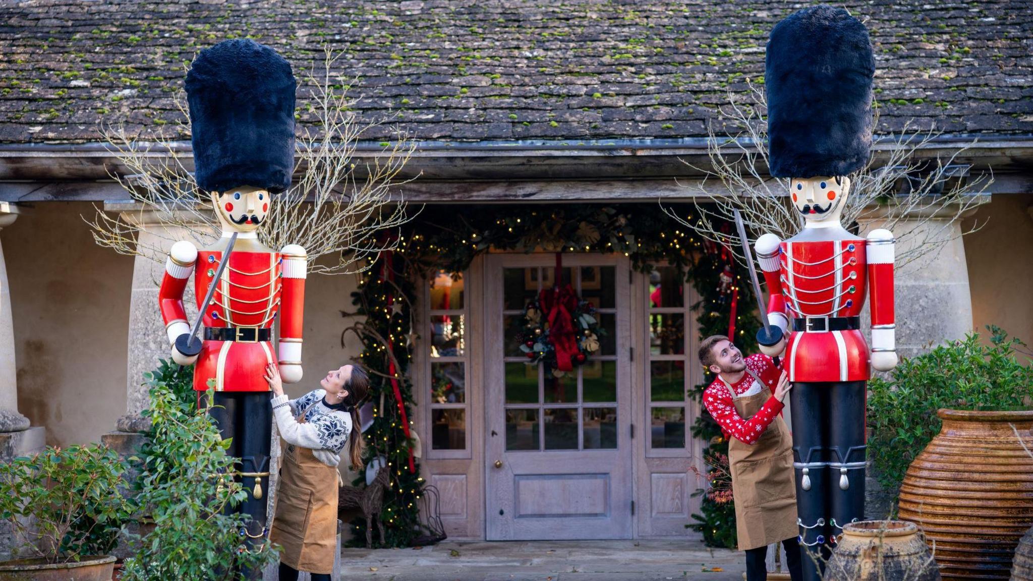 A pair of giant nutcrackers with their uniforms painted the colour of royal guardsmen in red tunics with tall black hats stand at the entrance to the function room at Highgrove
